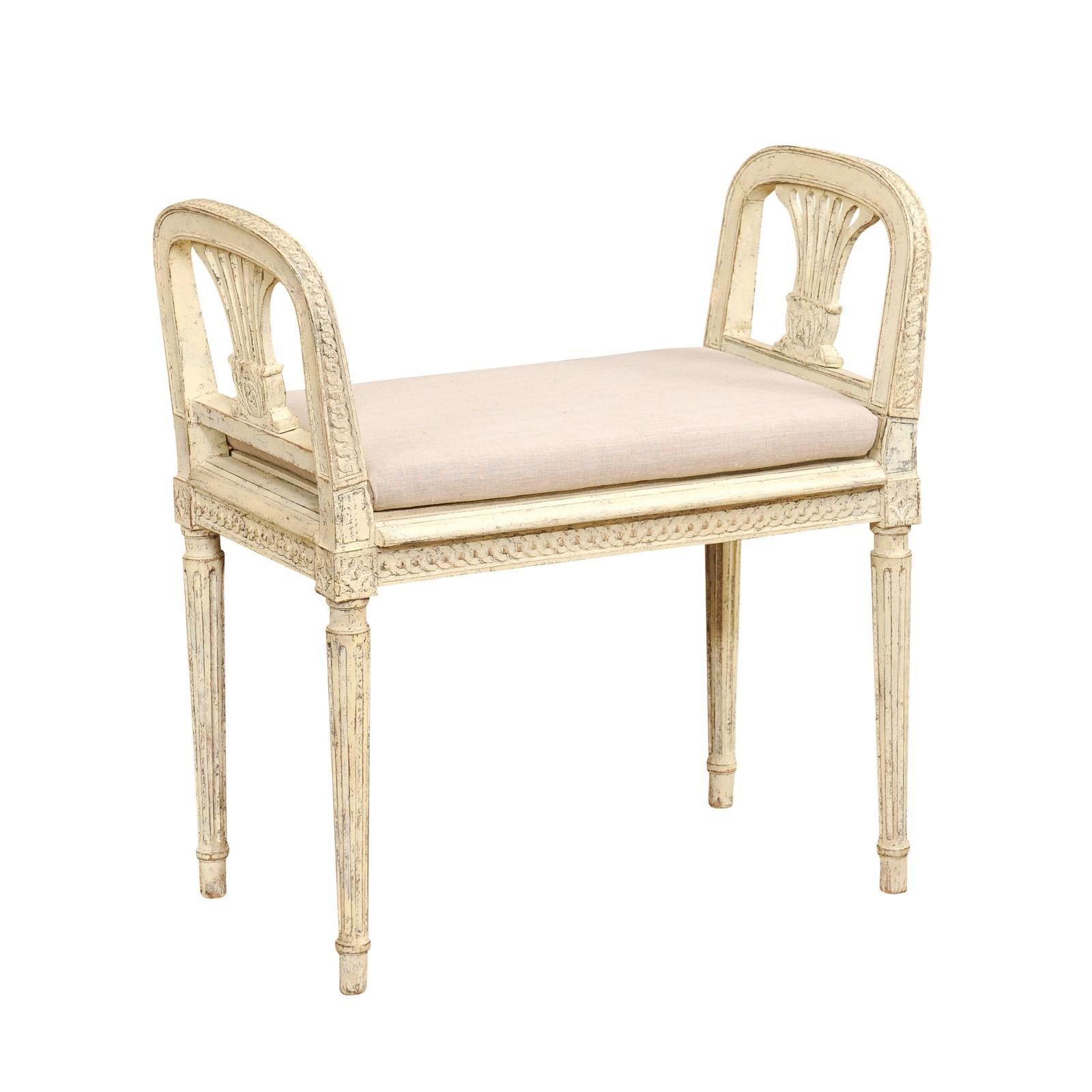 A Swedish Neoclassical style small bench from the 20th century with gray and cream painted finish, carved side supports, guilloche friezes and fluted legs. This Swedish Neoclassical style small bench, crafted in the 20th century, is a stunning