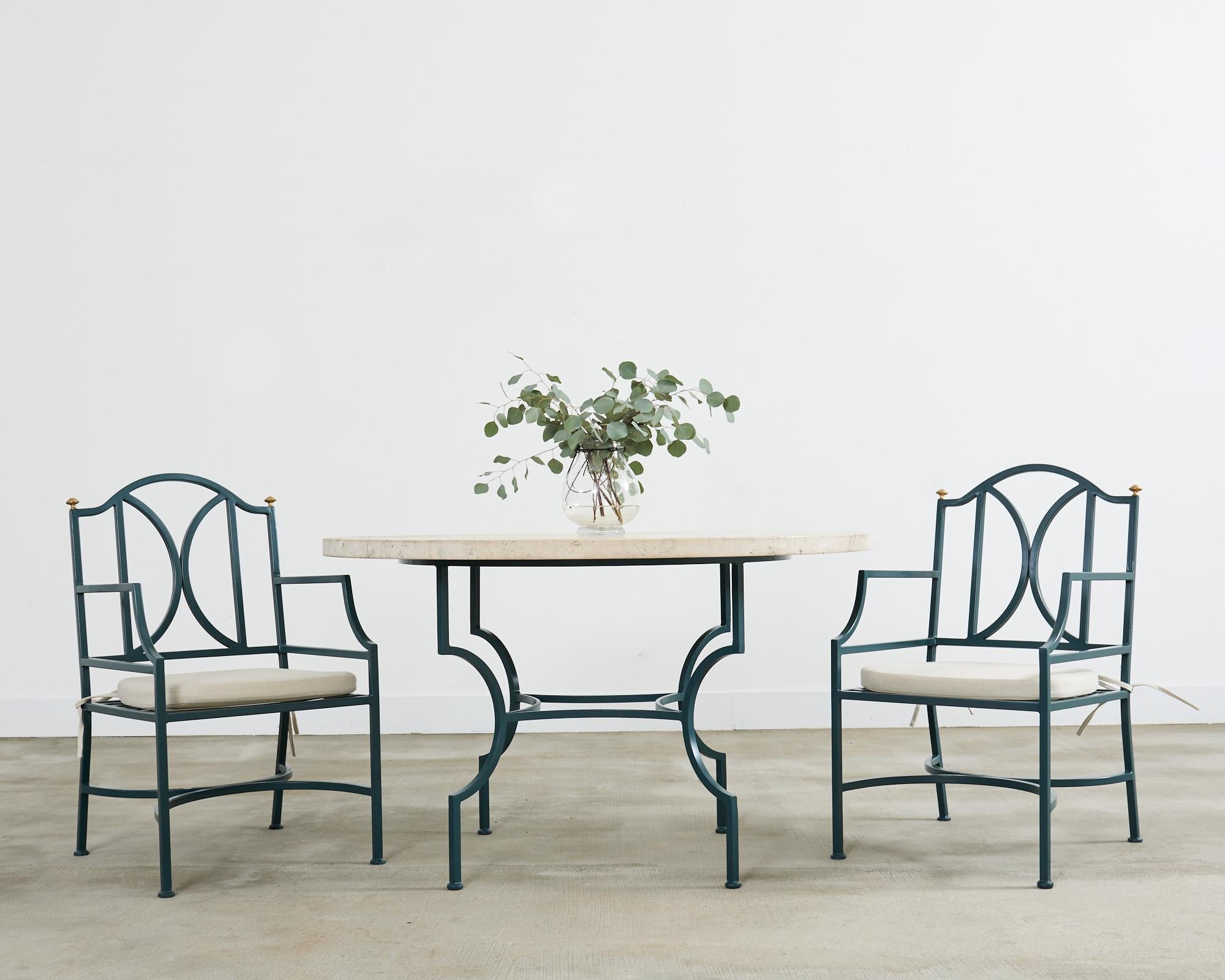 Table de patio et de jardin élégante dotée d'un plateau en travertin italien massif de 1,5 pouce d'épaisseur. La solide dalle de travertin est soutenue par un socle en fer de style néoclassique. La base est constituée de quatre pieds en forme de