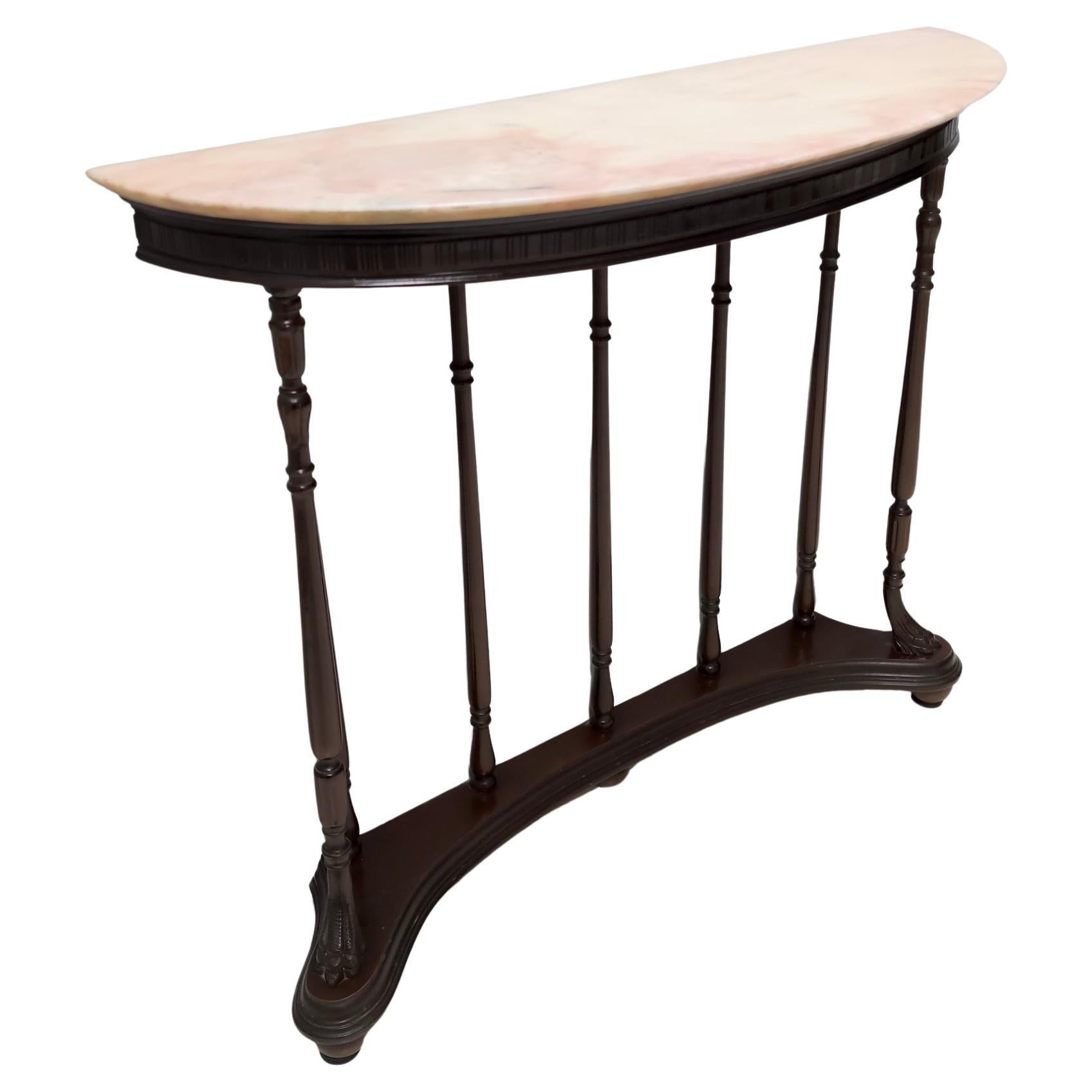Fabriqué en Italie, années 1960. 
Il se compose d'un cadre en hêtre tourné et d'un plateau en marbre rose portugais démilune. 
Cette console peut présenter de légères traces d'utilisation puisqu'elle est vintage, mais elle peut être considérée comme