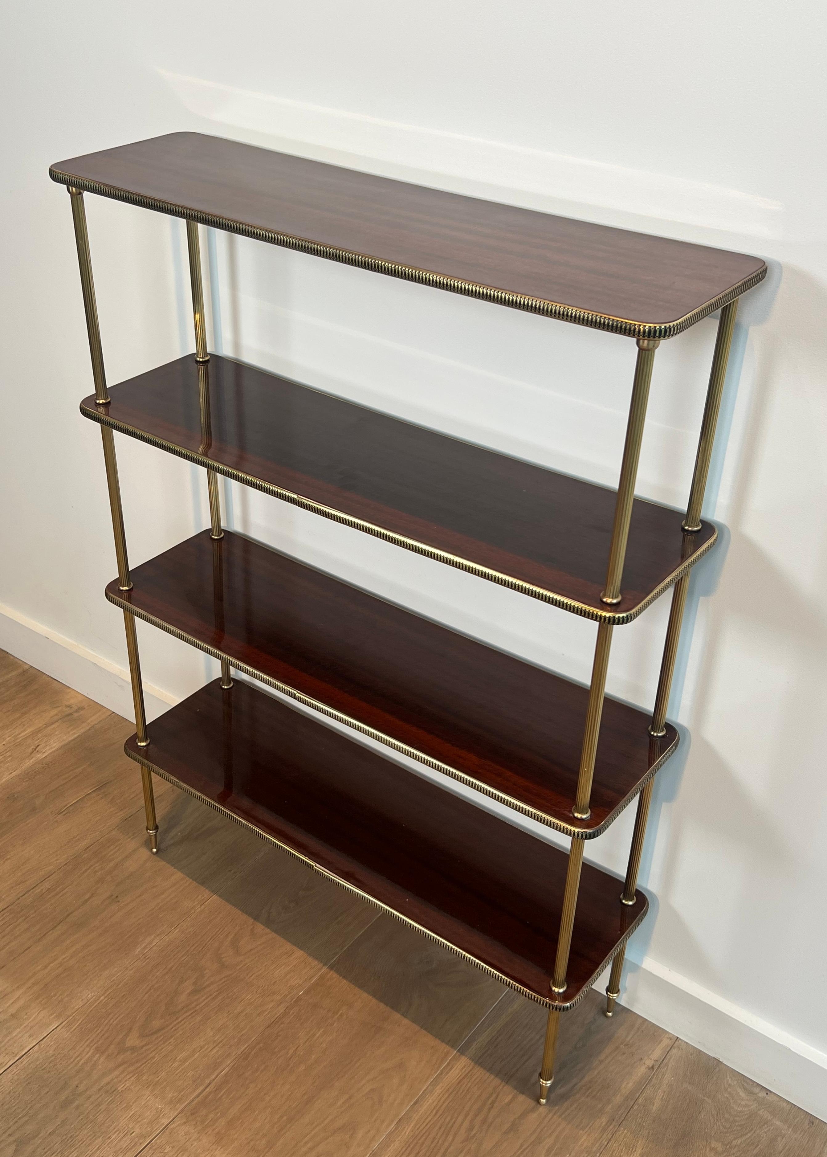 This neoclassical style shelves unit is made of wood and brass. This is a very elegant bookcase with 4 wooden shelves surrounded by a brass gallery. This is a French work in the style of Maison Jansen, circa 1940.