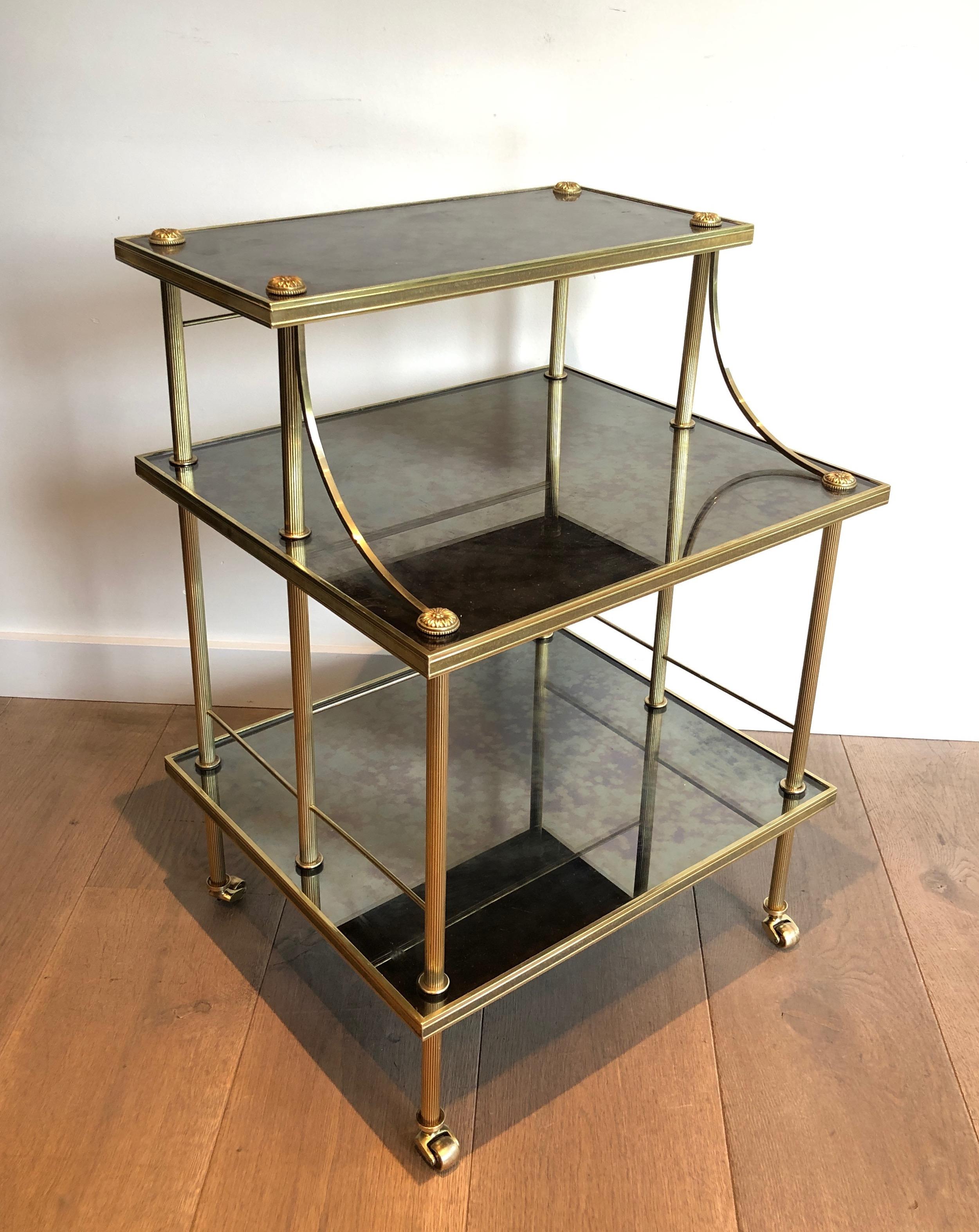 This very nice small shelves on casters with three tiers is made of brass with faux-antiques mirrors. This is a French work by Maison Jansen. Circa 1940