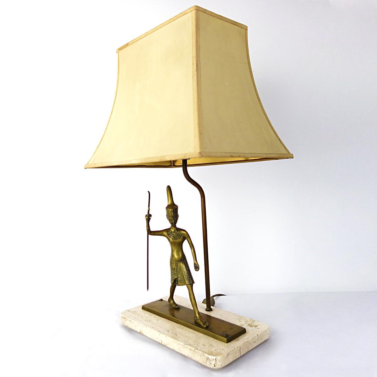 Very rare table lamp with a brass Egyptian warrior walking on a marble base. The shade, which is gold colored on the inside, provides for a warm light. A true personilty.