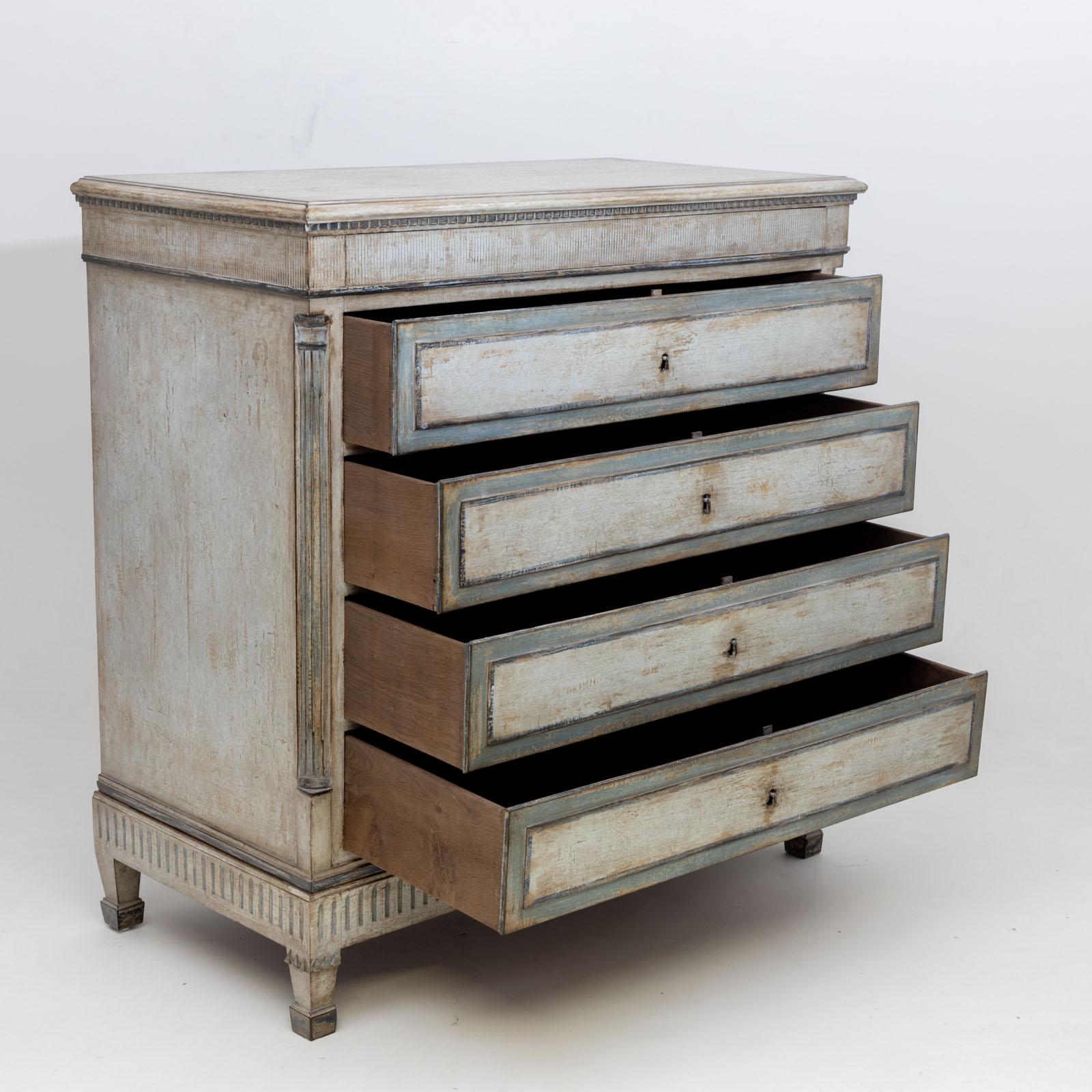 Large neoclassical chest of drawers with four drawers and a shallow drawer in the upper section. The chest of drawers is decorated with fluted quarter columns at the corners and a dentil frieze under the top panel. The light blue and cream-white