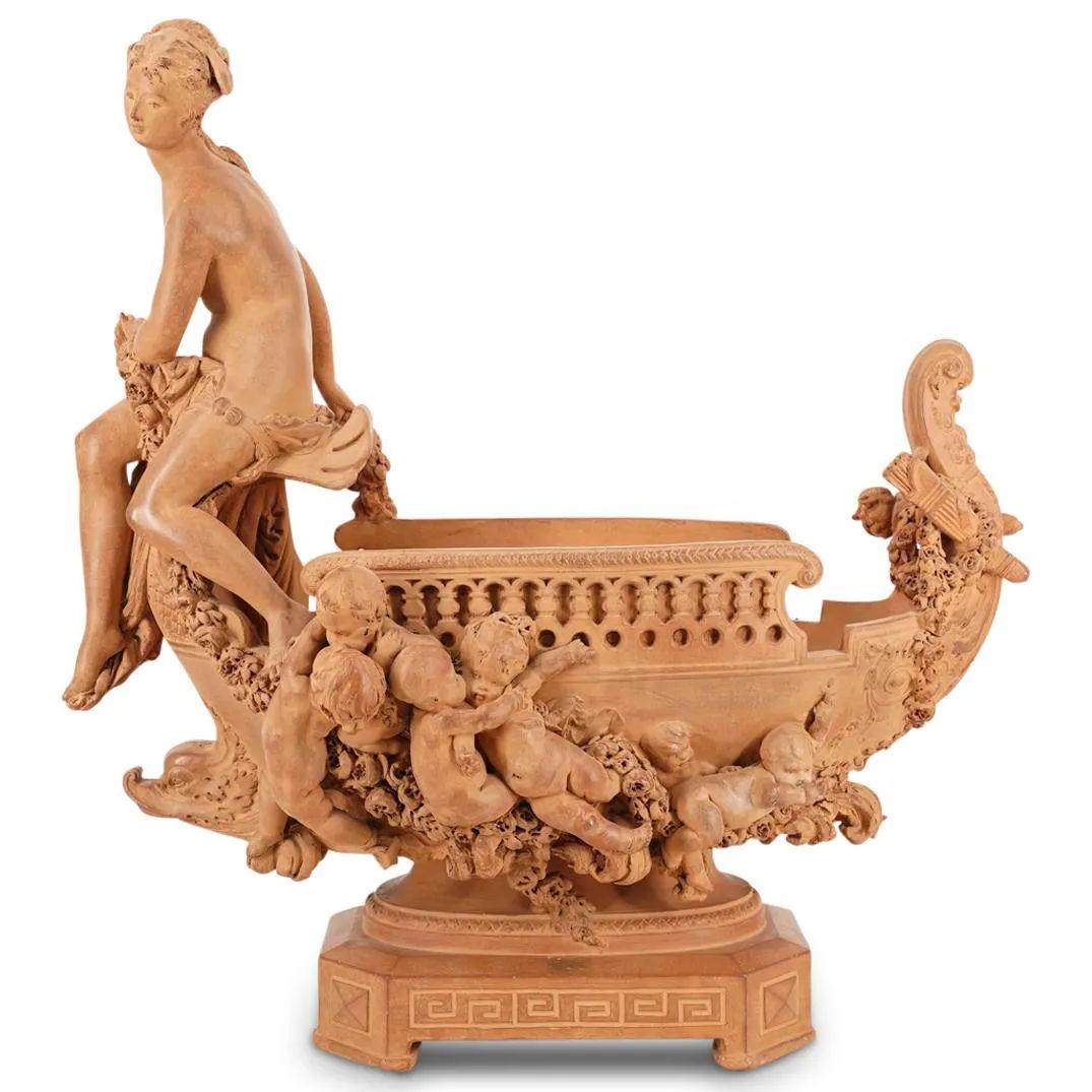 Our magnificent centerpiece bowl in terracotta by Gustave-Joseph Chéret (1838-1894) is fashioned as a Venetian gondola with Roman goddess seated at the bow and cherubs clinging to garland vines along the body, and mounted on a rectangular pedestal