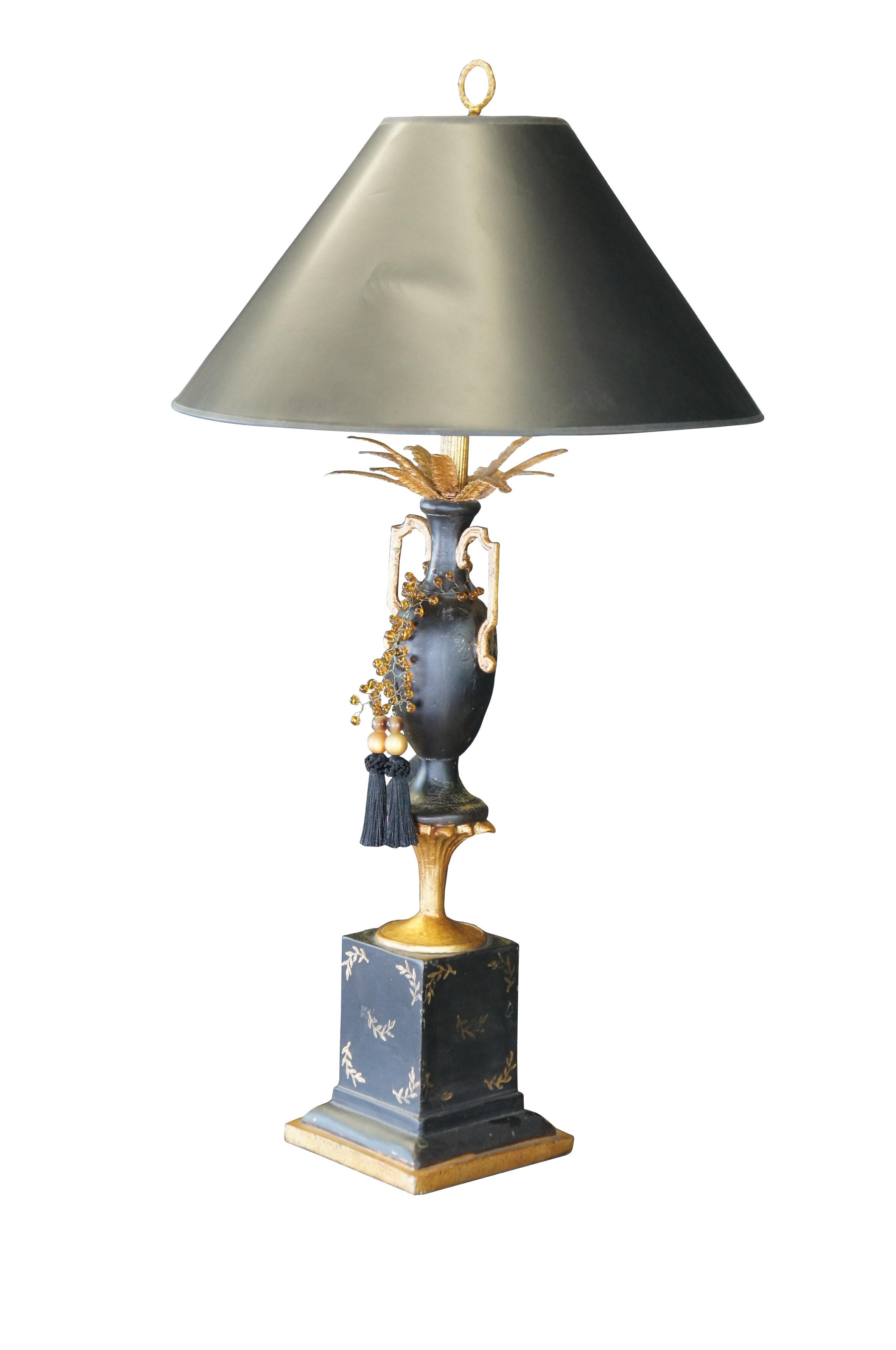 Neoklassizistische Lampe mit schwarzer und goldener Bemalung. Auf einem goldenen Sockel befindet sich eine Vase mit goldenen Federn und bernsteinfarbenen Perlenquasten.

Abmessungen: 
38 