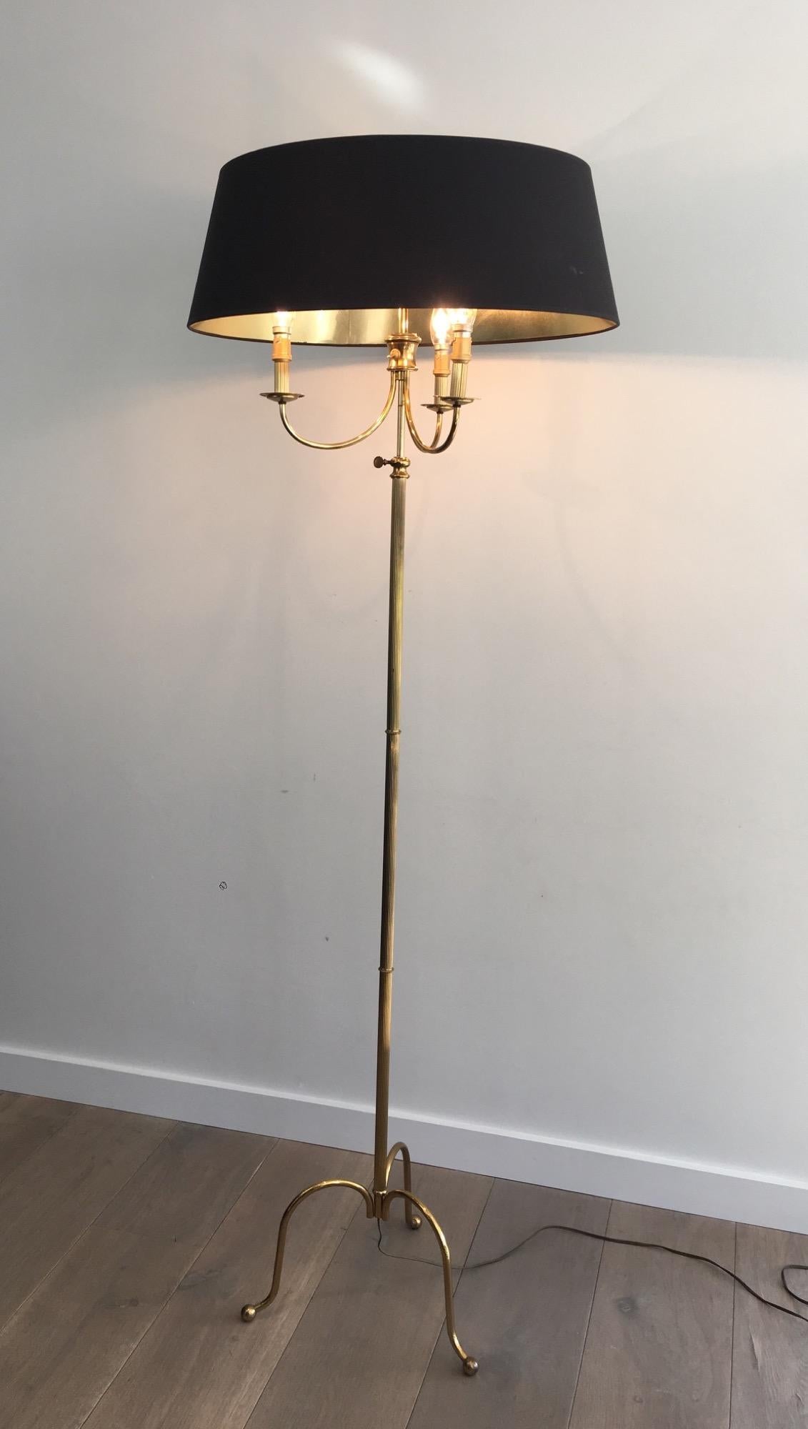 Diese neoklassische Tripode-Stehlampe ist aus Messing gefertigt und hat einen schwarzen, innen vergoldeten Shintz-Schirm. Die Höhe ist einstellbar. Es handelt sich um ein französisches Werk im Stile von Maison Jansen. CIRCA 1940