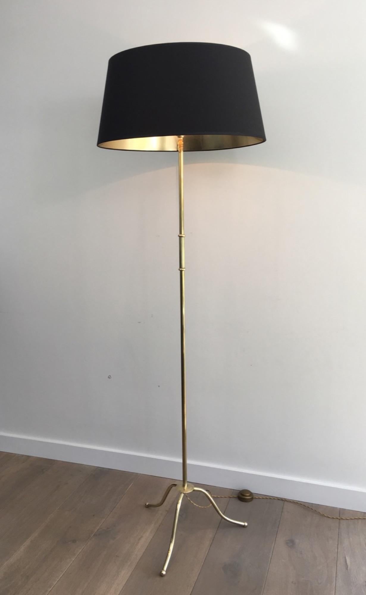 This neoclassical floor lamp is made of brass. It has a tripode base and a black shintz shade gilt inside. It is French, in the style of Maison Jansen, circa 1940.
