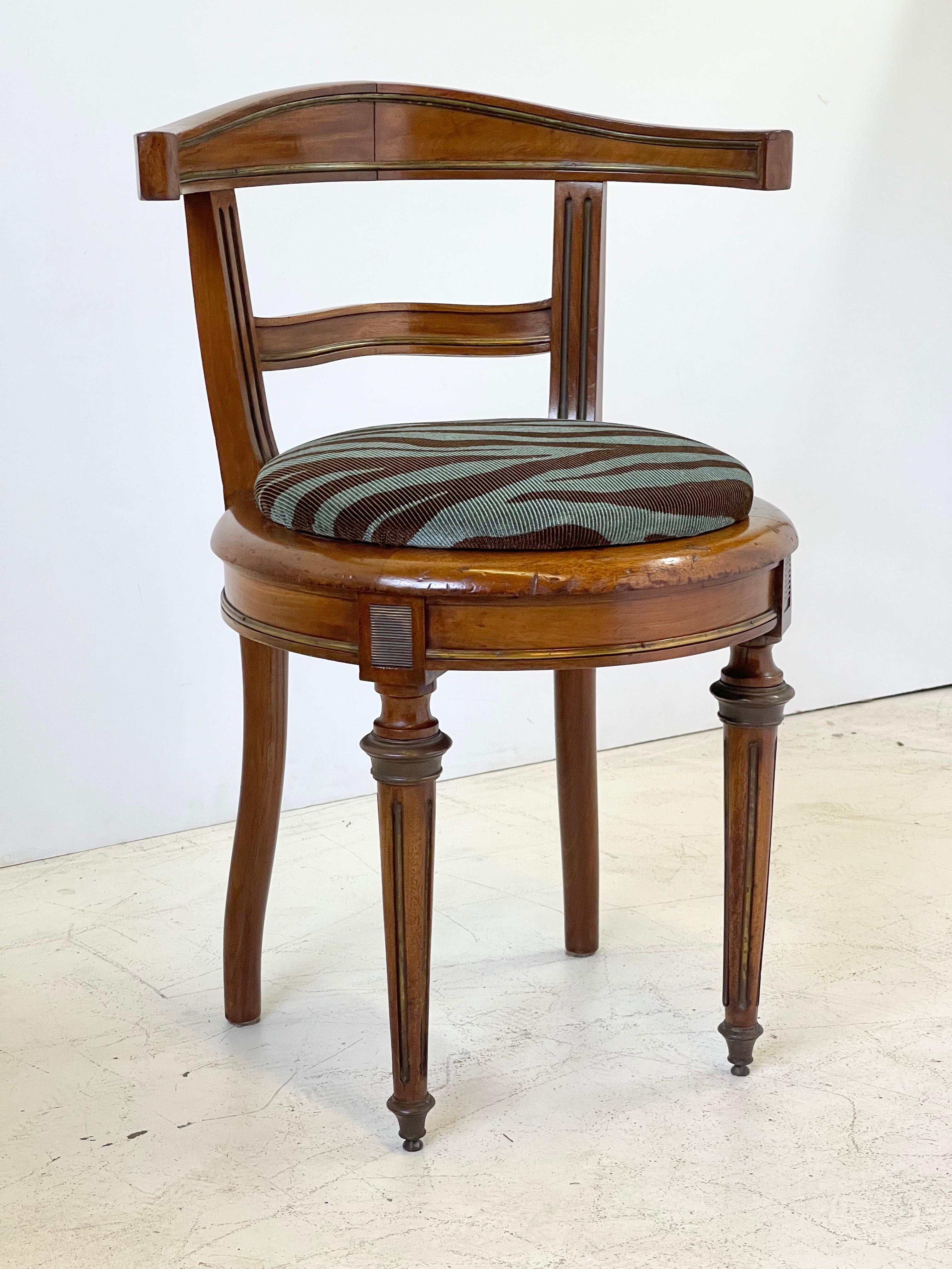 Early 20th century Italian neoclassical vanity chair made of walnut with brass inlay. The round raised seat cushion is covered in a blue and brown ribbed zebra print fabric.