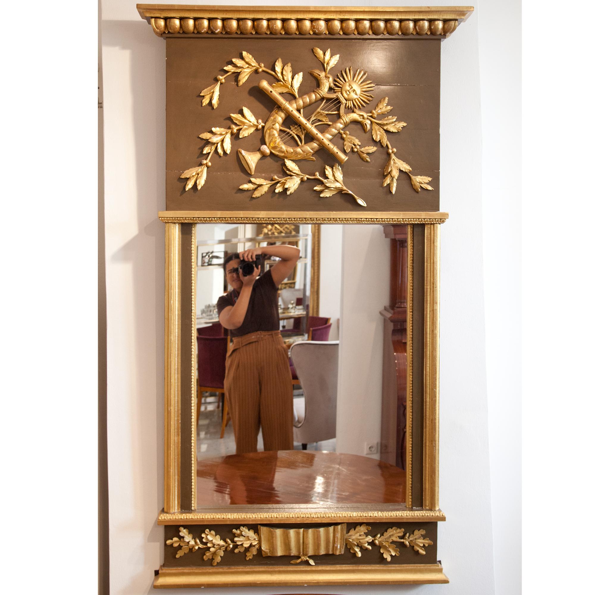 Wall mirror with applied sun ornament and decorations in the form of lyre, fruit and oak leaf decorations and a kymation frieze at the top.