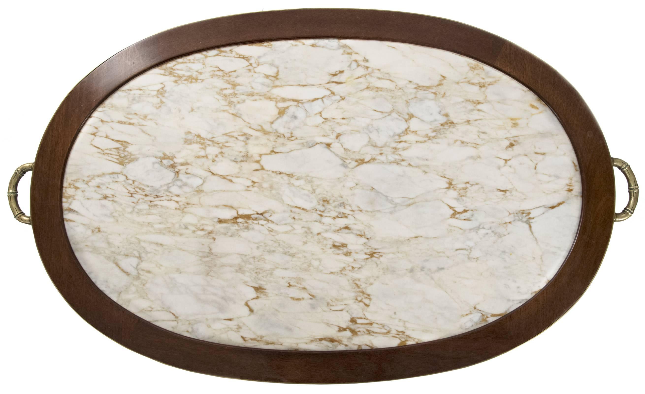 A 19th century neoclassical style oval coffee table with marble inset a walnut top with brass trim affixed with bamboo-formed handles, supported on an unadorned apron with shoulder-mounted brass rosettes above round tapered legs with brass capped