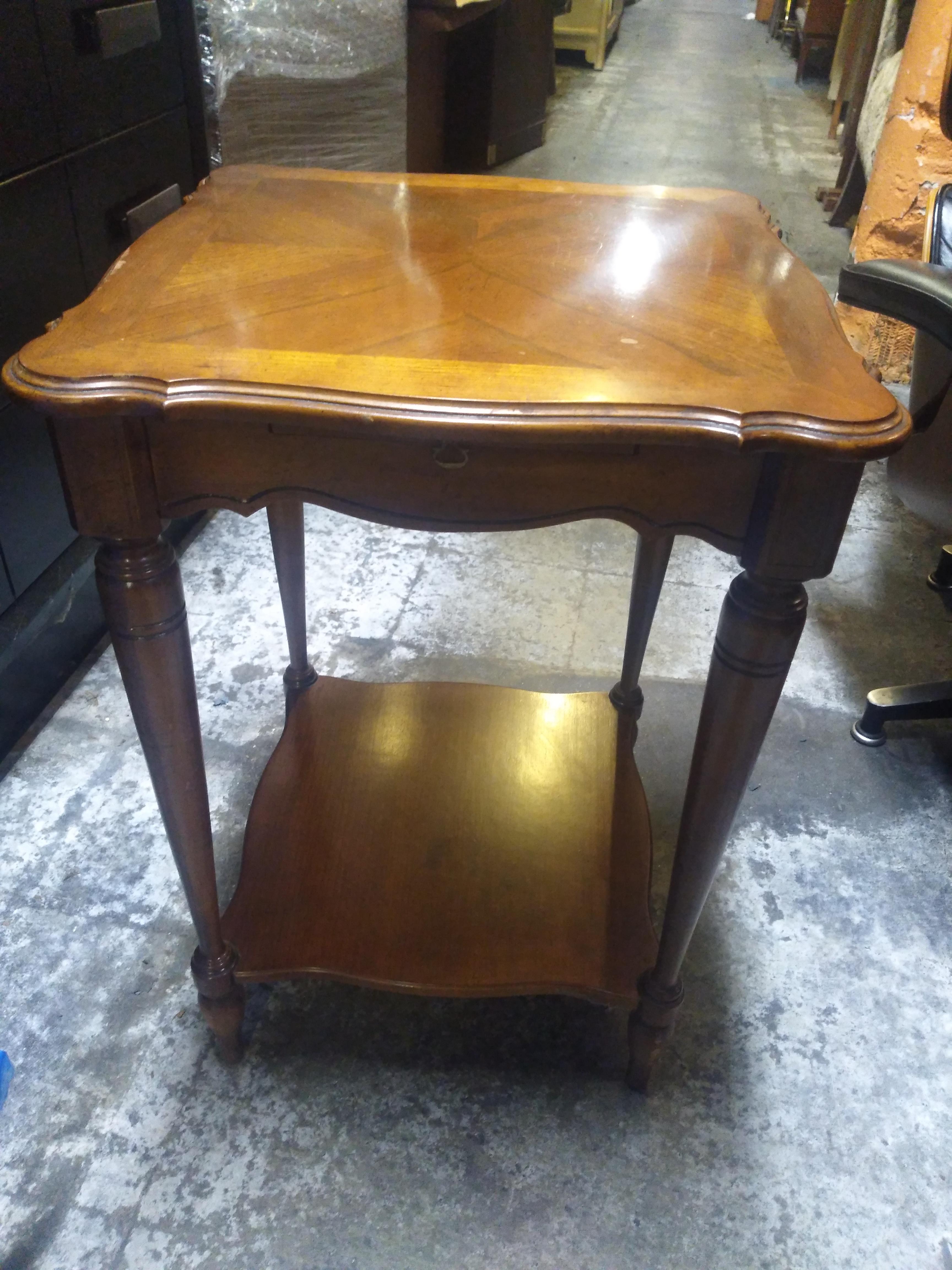 This beautifully crafted table by Lane Furniture is made of walnut. To has a pull out tray for beverages and a lower shelf for storage. The turned legs give this pedestal table a look of elegance.
