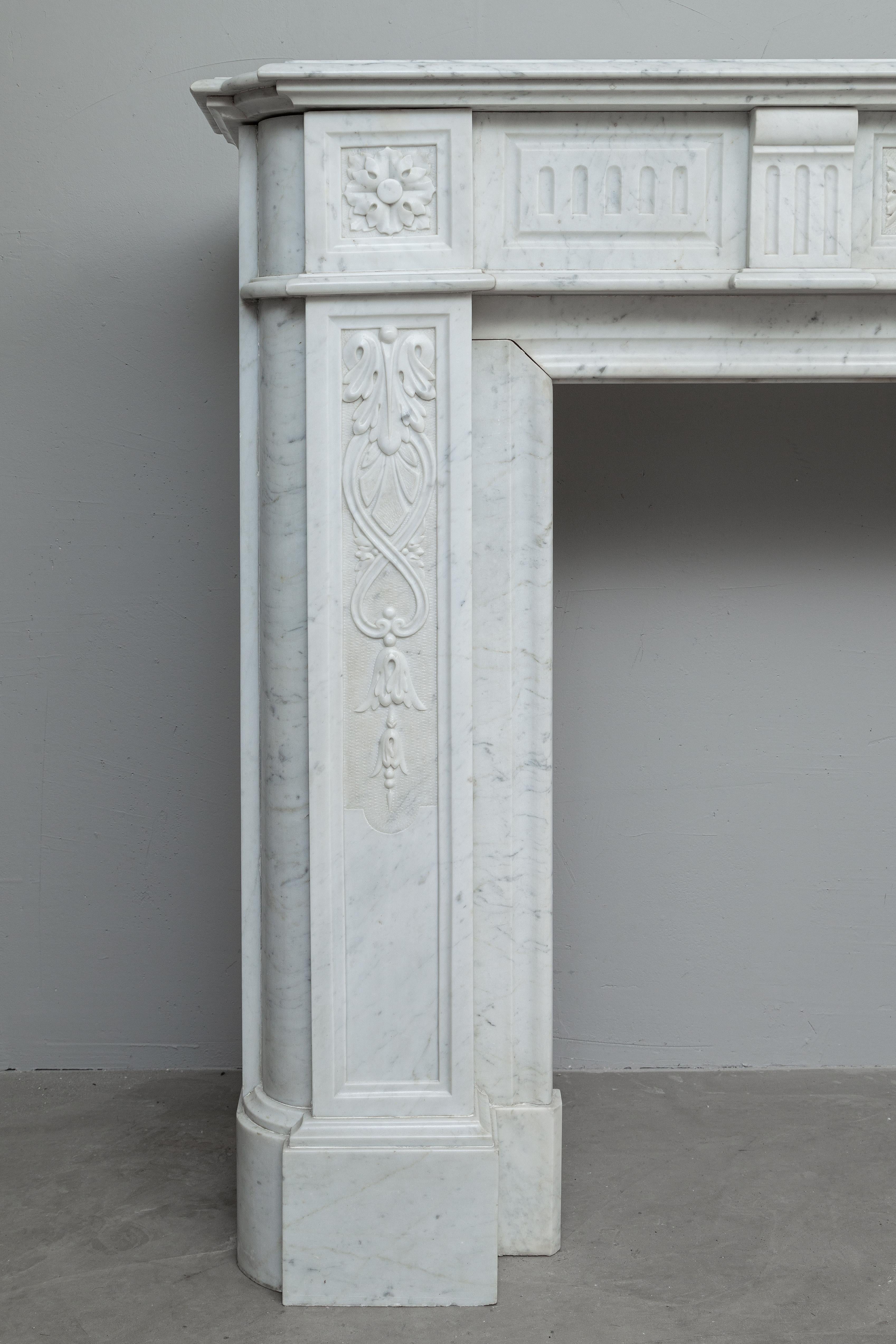This fireplace, executed in the beautiful clear white Carrara marble, exudes luxury. The round corners that continue from the plinth to the top give this fireplace its elegant appearance. The subtly elaborated legs with flower and leaf motif, the 2