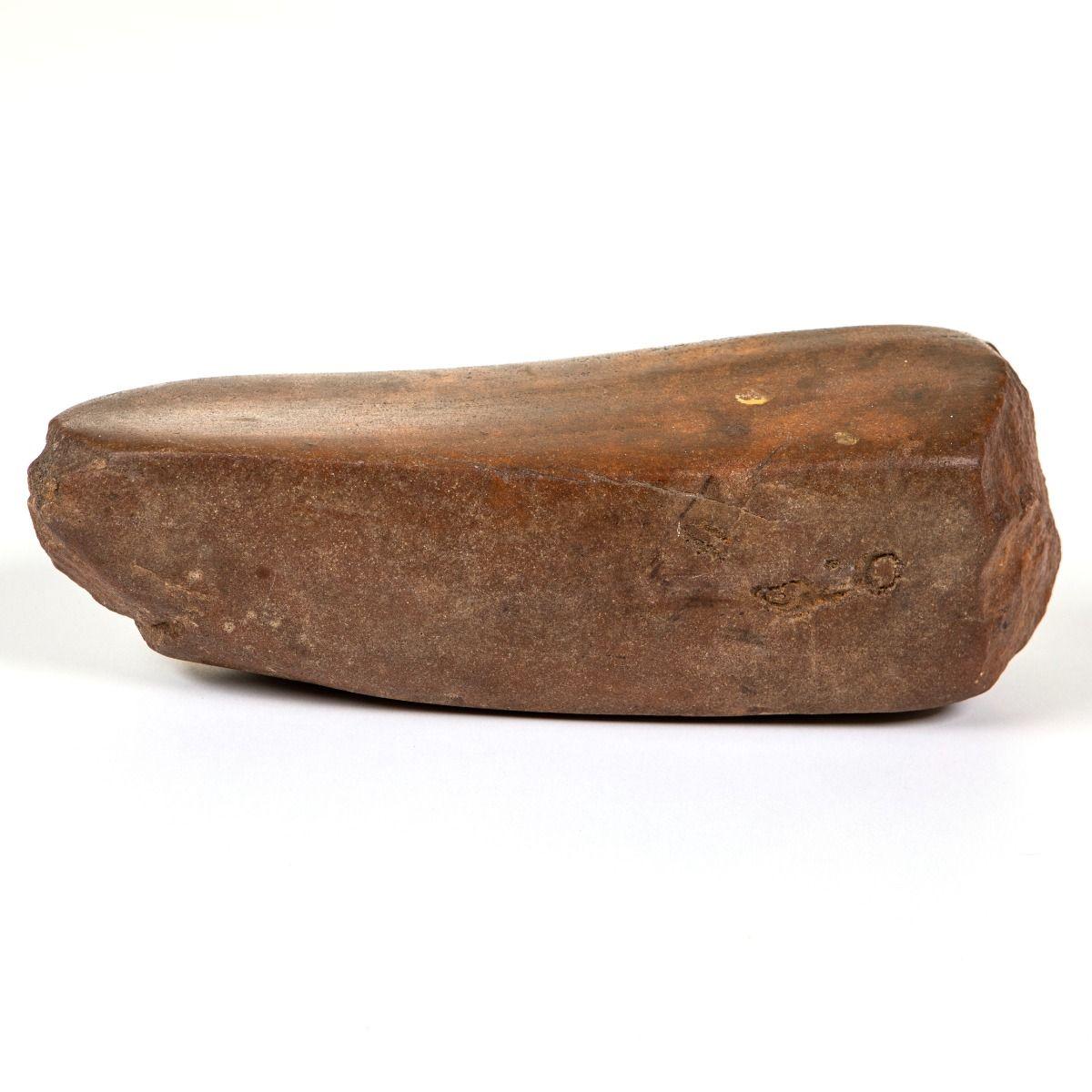 Grinding stone used for sharpening and polishing flint tools during the Stone Age. The surface is smooth and slightly curved, shaped through prolonged use. It was likely employed to maintain and sharpen ground flint axes, chisels, and similar