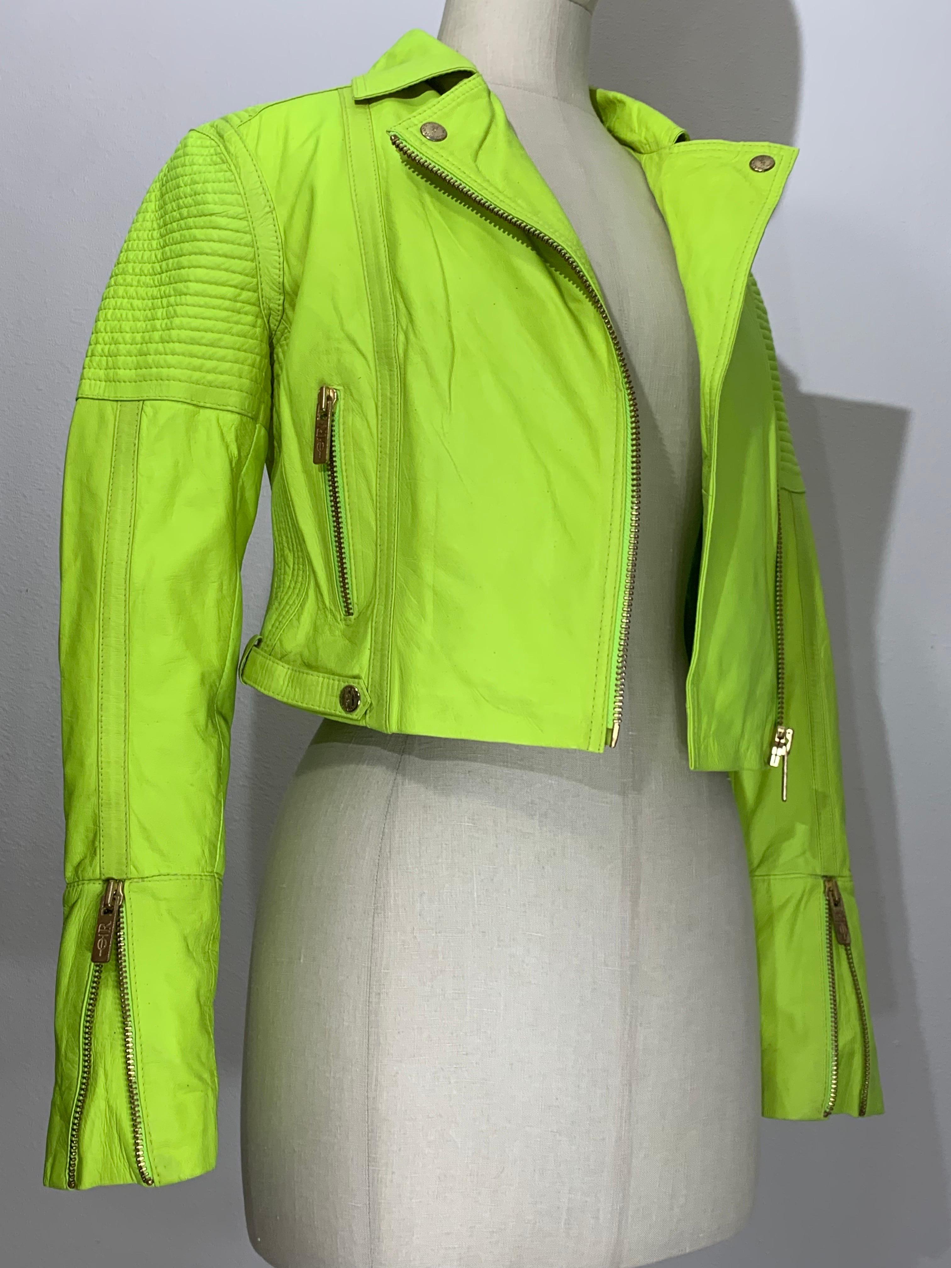 Neongrüne Lederjacke im Motorrad-Stil mit gesteppten Schultern und Reißverschlüssen:  Asymmetrischer Reißverschluss, Schlitztasche mit Reißverschluss vorne und spitz zulaufende Ärmel mit Reißverschluss. Die Schulterpartien sind für einen
