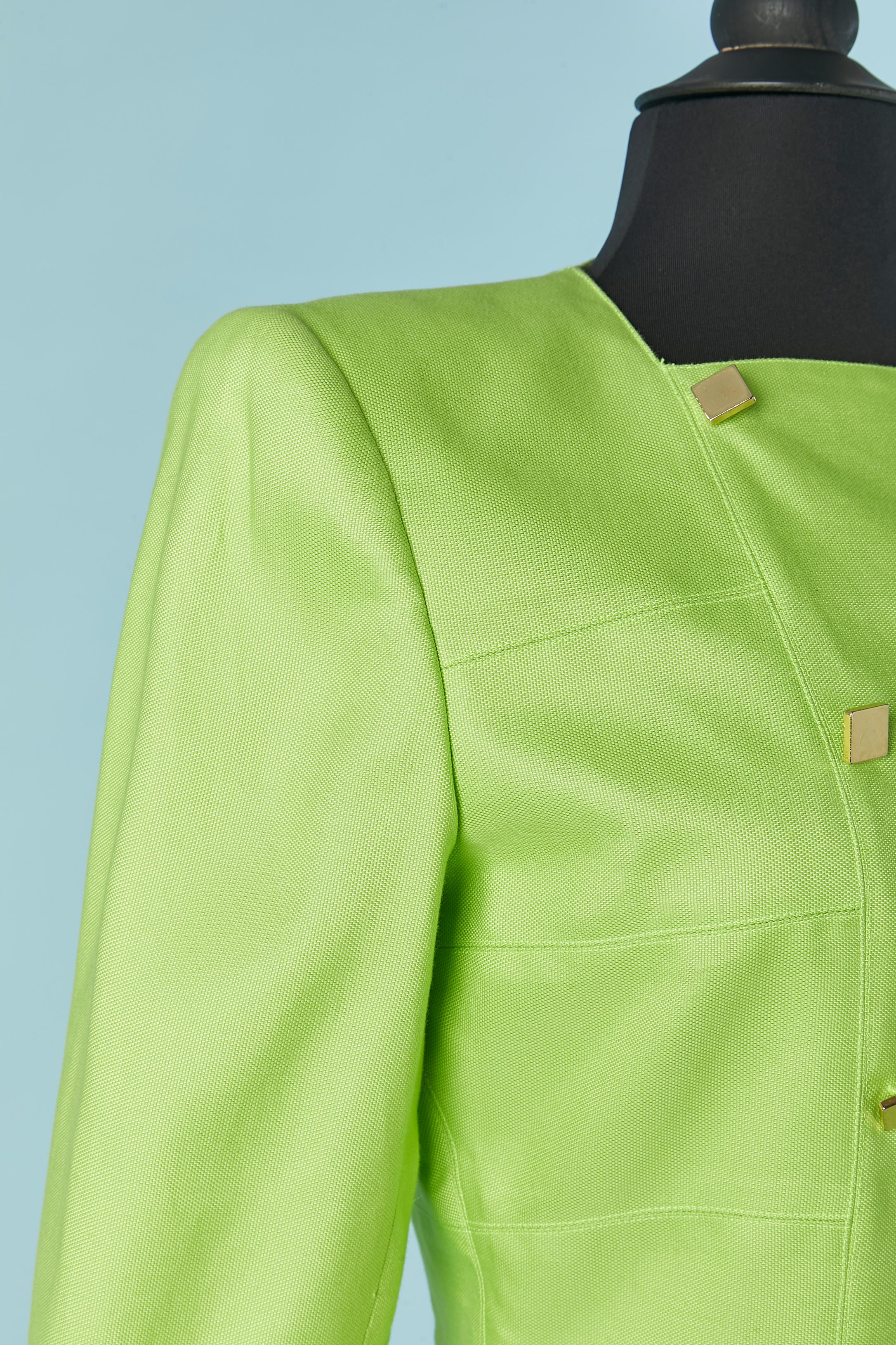 Neon green skirt suit with double-breasted jacket. Main fabric composition: cotton and rayon. Lining composition: acetate and rayon.
Gold metal square button and buttonhole on the front of the jacket . Same on the cuffs. Shoulder pad. Pocket on both