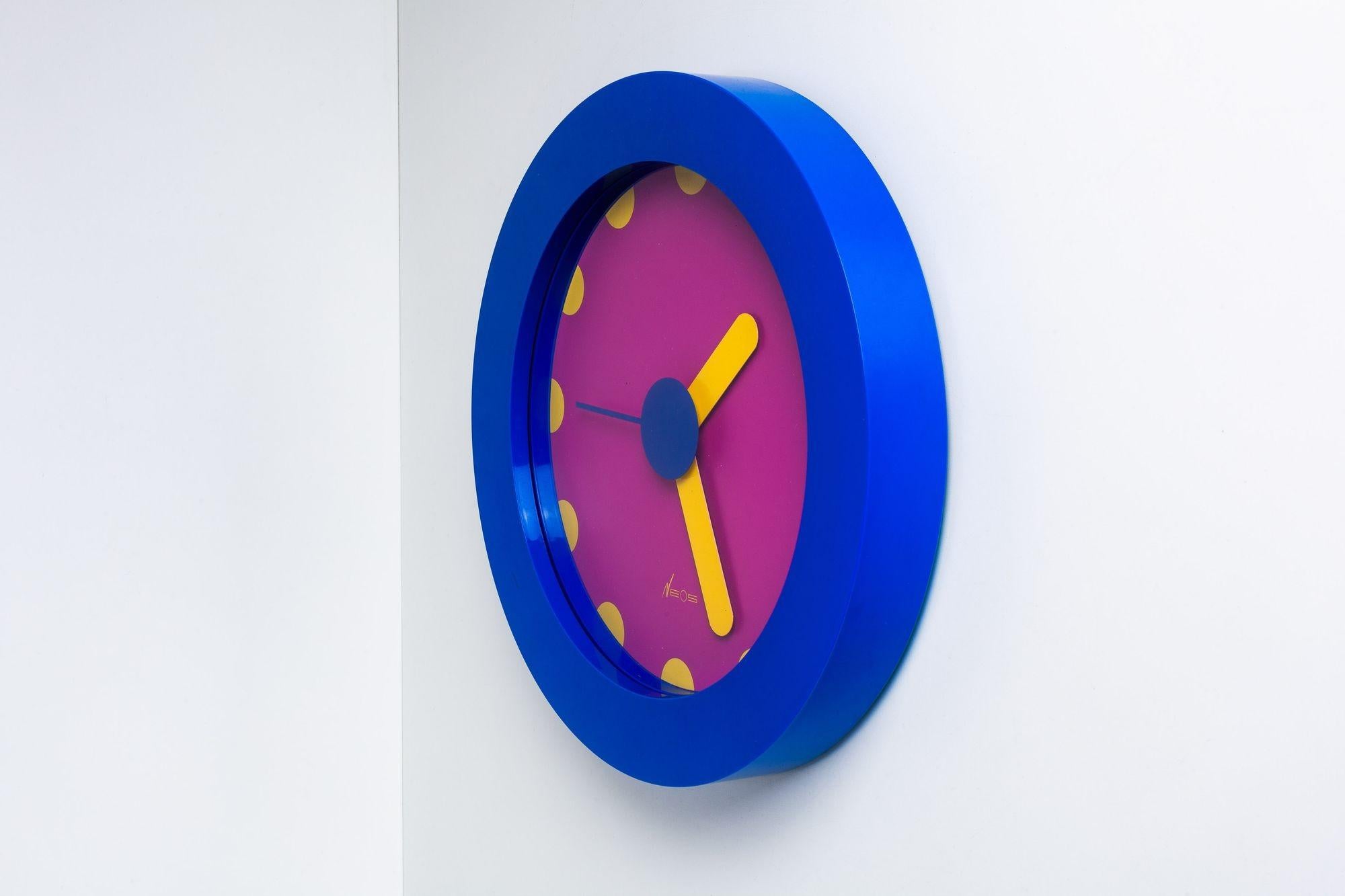 Neos Lorenz du Pasquier & Sowden Postmodern Clock
A blue and purple plastic postmodern wall clock with yellow hands and numbers designed by Nathalie du Pasquier and George Sowden for Neos of Lorenz in the late 1980s.
Co-founders of the Memphis