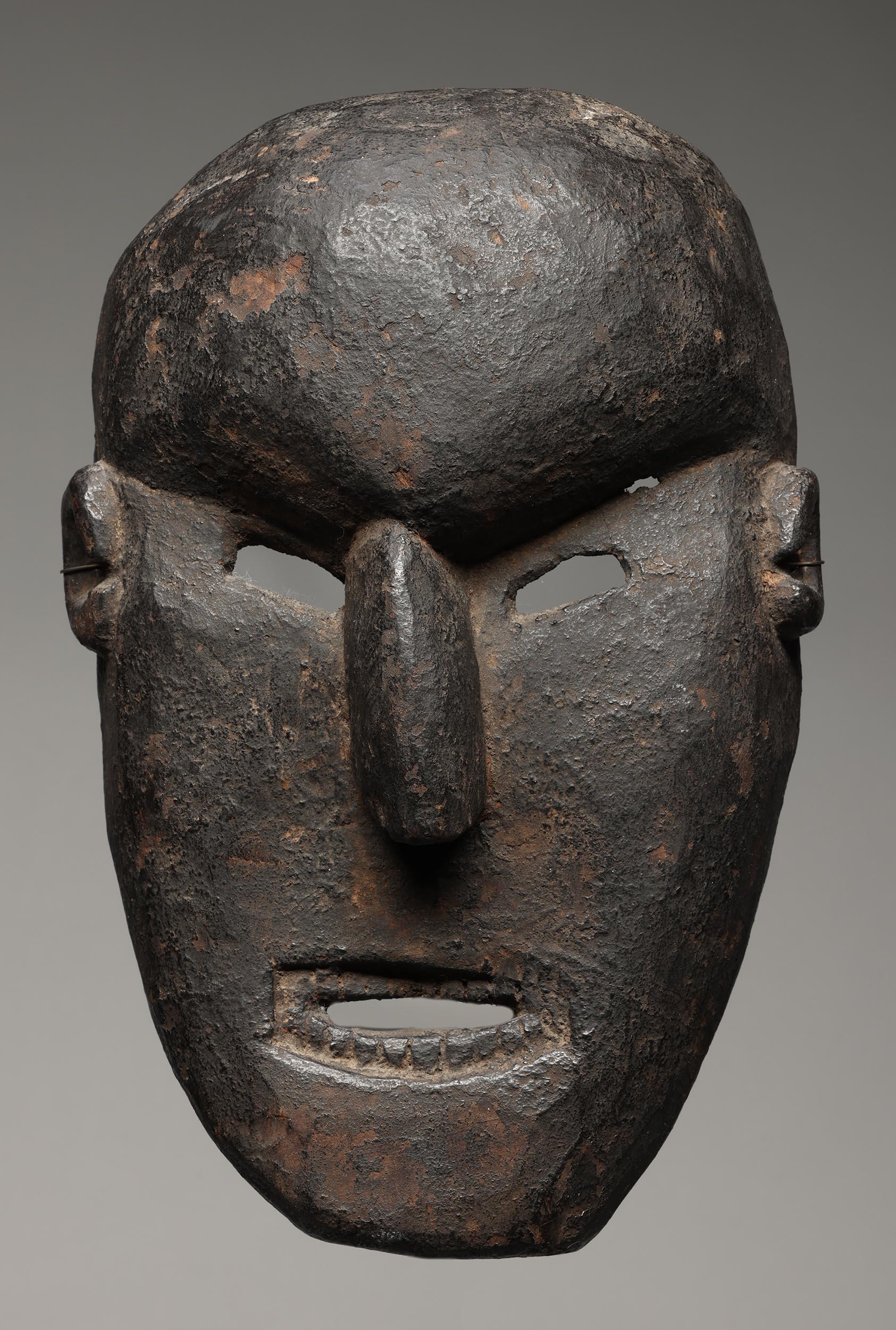 Masque de danse ovale du Népal avec une expression puissante, des yeux ouverts et une bouche ovale avec des dents finement sculptées, des oreilles joliment sculptées. Forte patine noire incrustée à l'intérieur et à l'extérieur due à l'utilisation