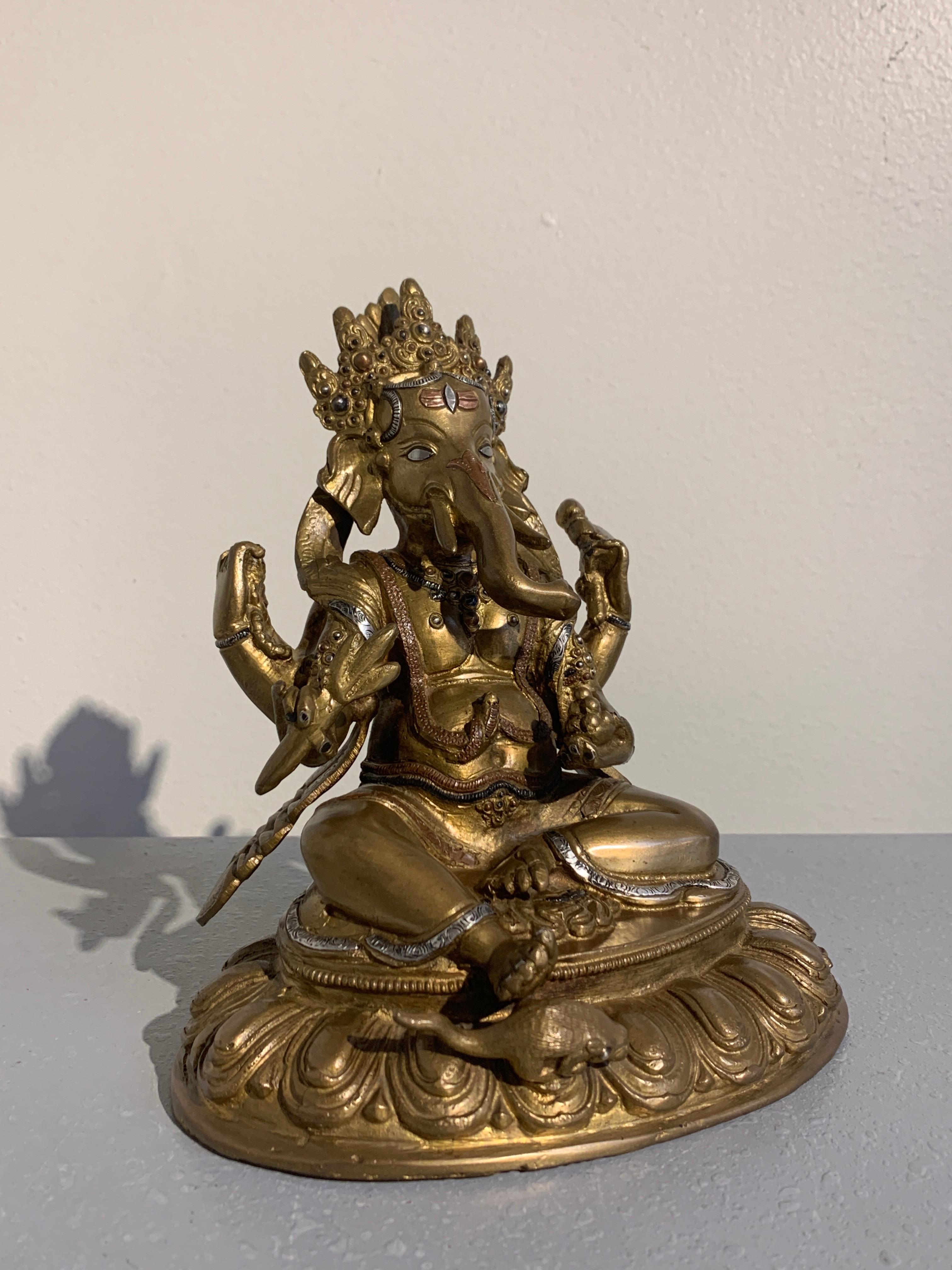 A charming and unusual figure of the Hindu god, Ganesha, Remover of Obstacles, featuring inlays and overlays of copper and silver, Nepal, 1970s. 

The beloved elephant headed deity, known as Ganesha, Ganesh, Ganapati, sits upon a lotus pedestal in