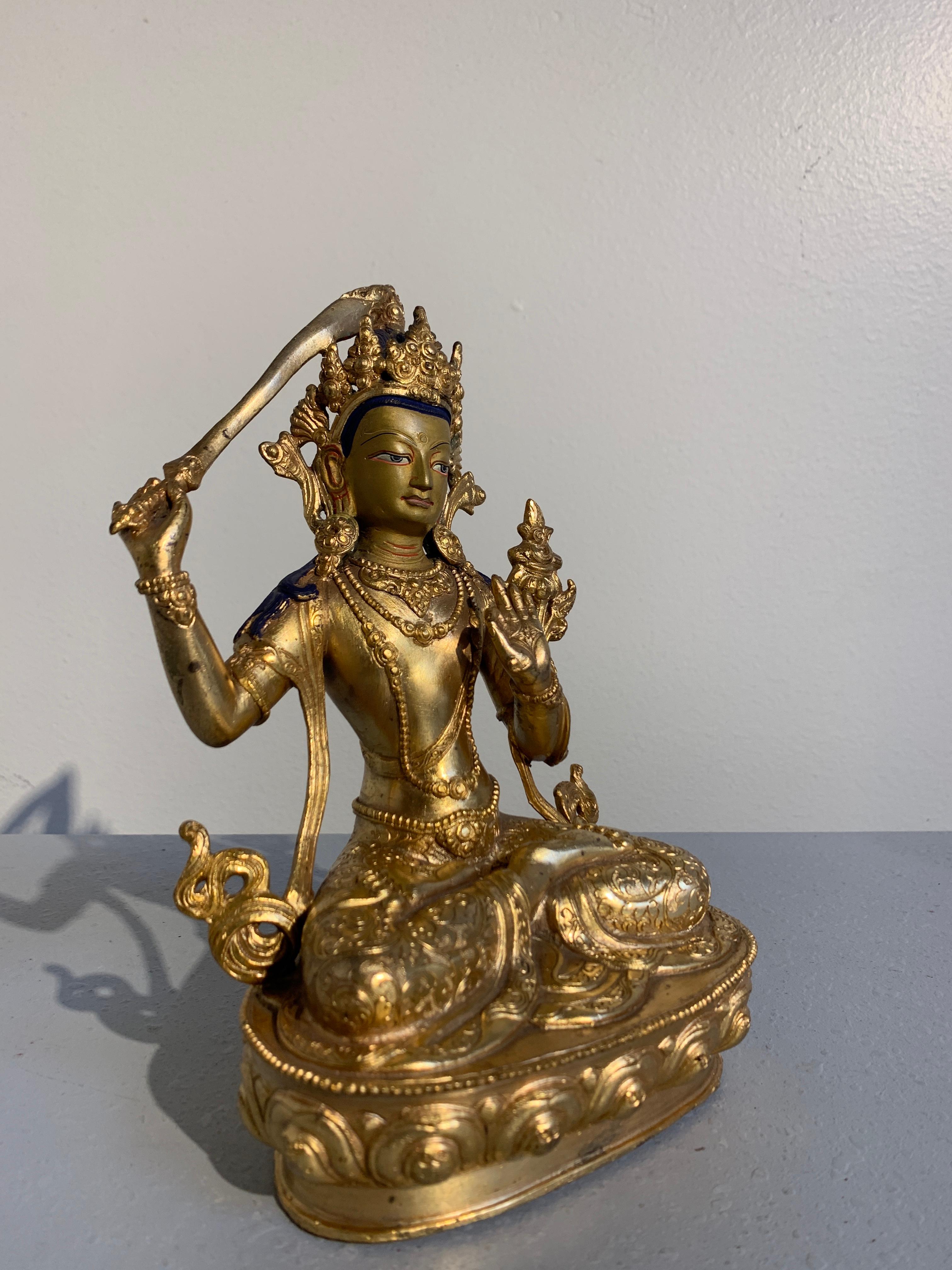 Belle figure népalaise en bronze doré représentant Manjushri, le Bodhisattva de la sagesse, datant du début ou du milieu du XXe siècle. 

Le Bodhisattva de la sagesse transcendante est assis sur un piédestal en forme de lotus, les jambes croisées