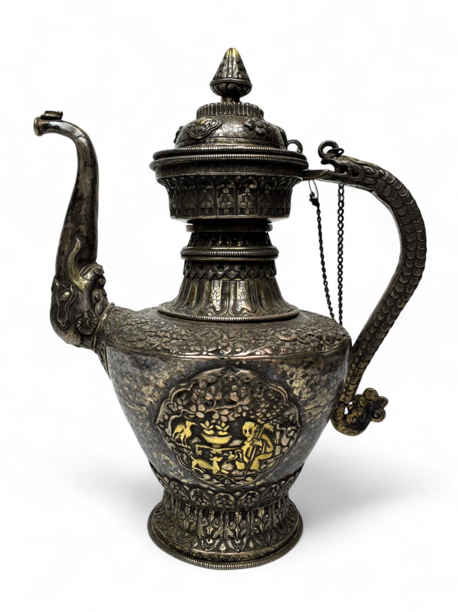 Antique Nepalese Silver Ritual Ewer with Gilded Repoussé Panels
Circa late 19th – Late 19th century  Kathmandu Valley, Nepal
Dimensions: Height: 12 in. (30.5 cm) x Width: 10 in. (25.5 cm)

A commanding and intricately adorned ceremonial ewer from