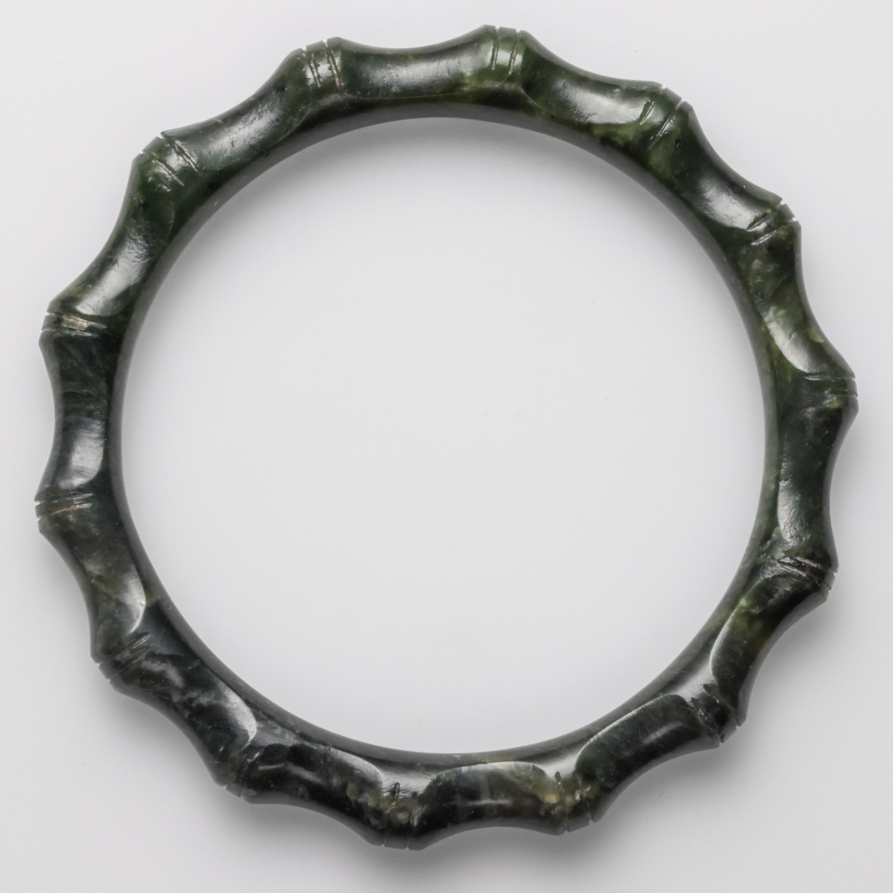 This deep green nephrite jade bangle was hand-carved in the early 1950s to resemble segmented bamboo. It displays the pre-industrial revolution polish of that era, before electric tools and diamond polishing compounds were in wide usage in China.
