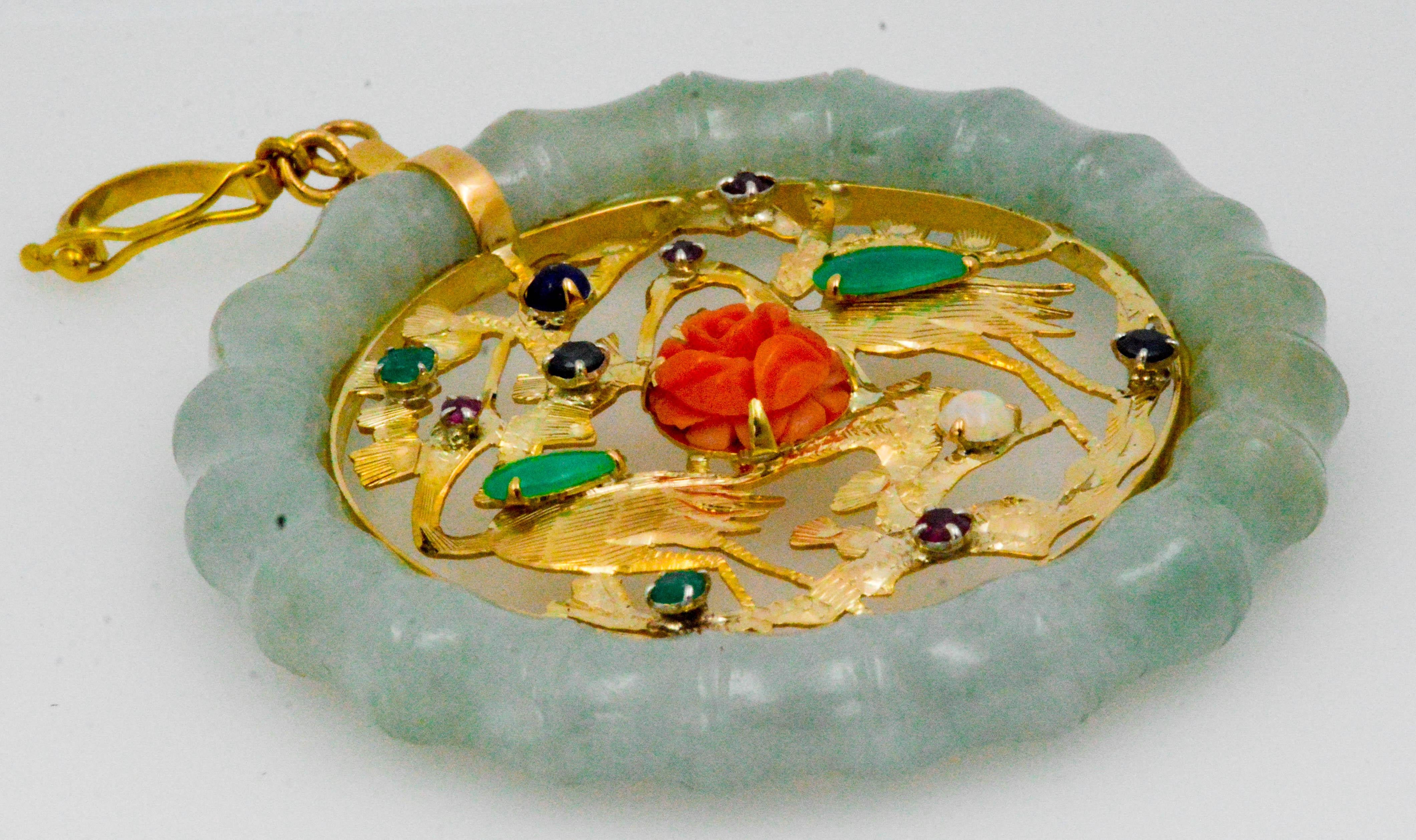 An expertly carved rosette coral (7.84 mm) is the centerpiece of this interesting Nephrite Jade pendant. With two carved 14 karat yellow gold cranes set with teardrop shape jade bodies and either ruby or emerald eyes. Adorning the intricately carved
