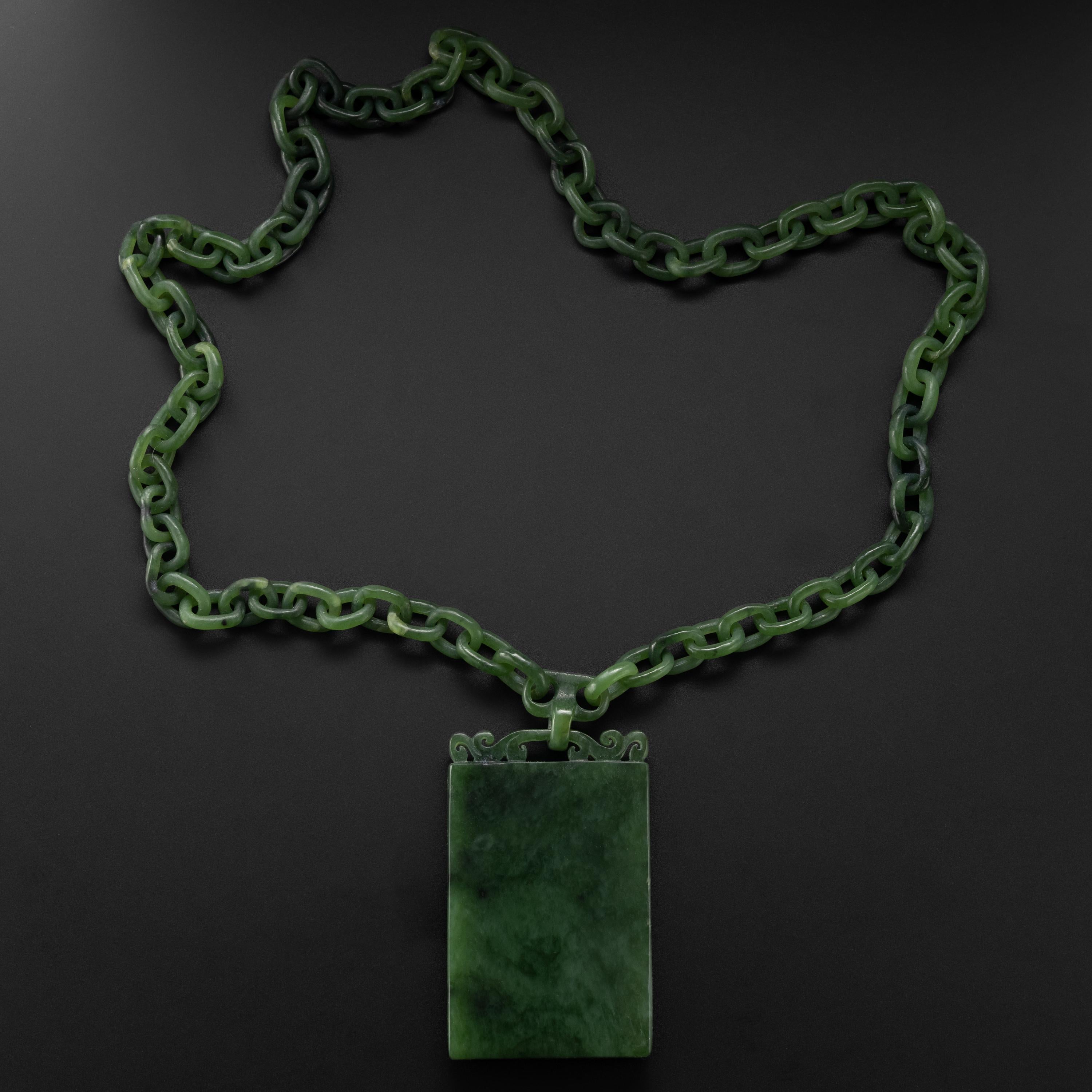 This is an utterly magnificent and unique necklace entirely hand-carved by a Chinese lapidary artist. The two carved chains meet on the carved bail of the pine-green nephrite jade plaque, highly polished on both sides. This is a spectacular and