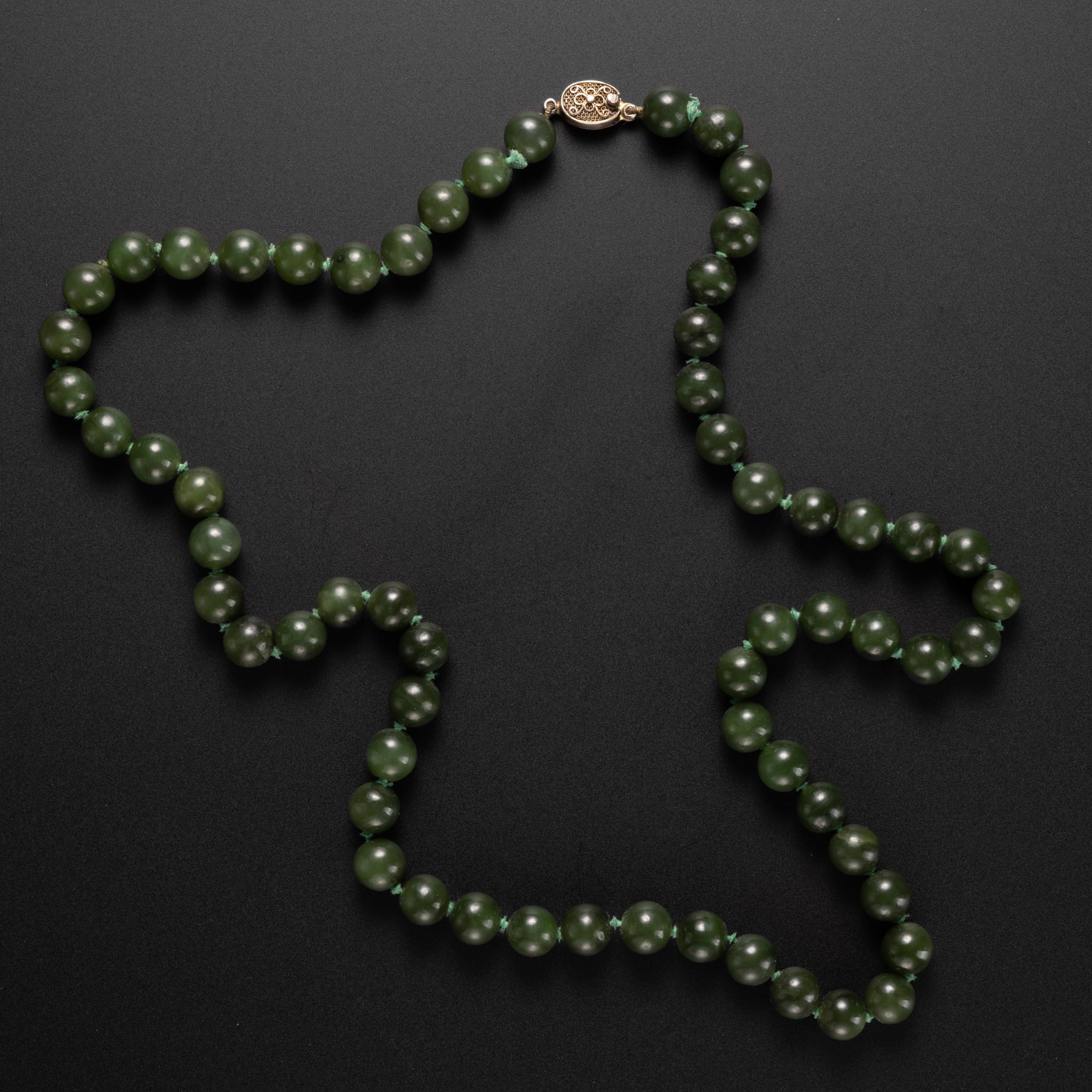 The hand-carved nephrite jade beads that compose this necklace are a deep olive green with a bright luster. The 62 beads measure between 9.93 - 10.31mm. The overall length is just shy of 28