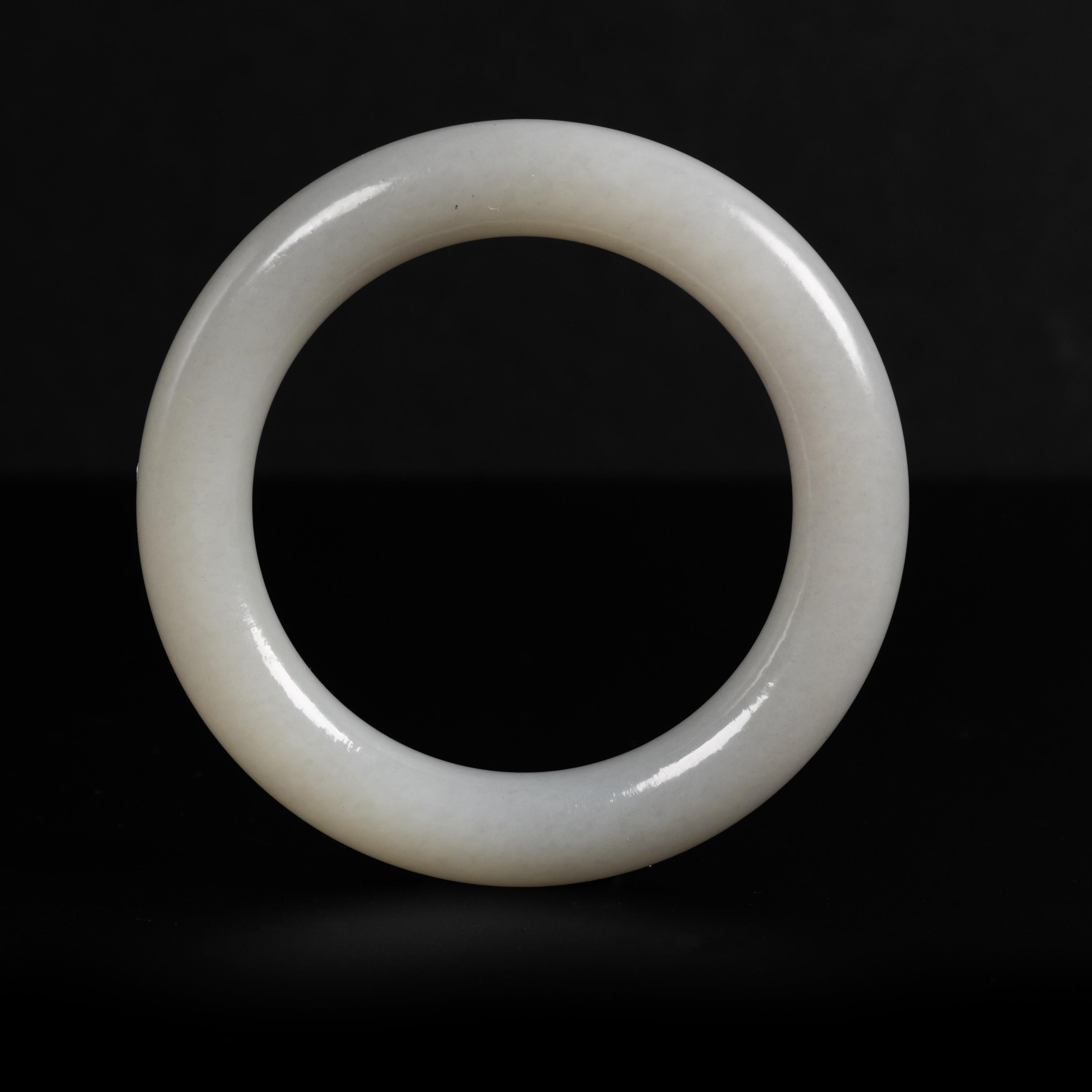 This 59mm hand-carved pale grayish-green nephrite jade bangle has been carved in the traditional round form that has been worn in China for thousands of years. Simple it may be, unadorned and free of decoration: but the jade is luminous and