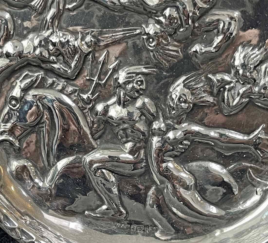 Bursting with joy and great energy, this sterling silver wine coaster features Neptune with his trident, riding a hippocampus, accompanied by teeming array of oceanic creatures, including mermaids, mermen, tritons and one of the four gods of the