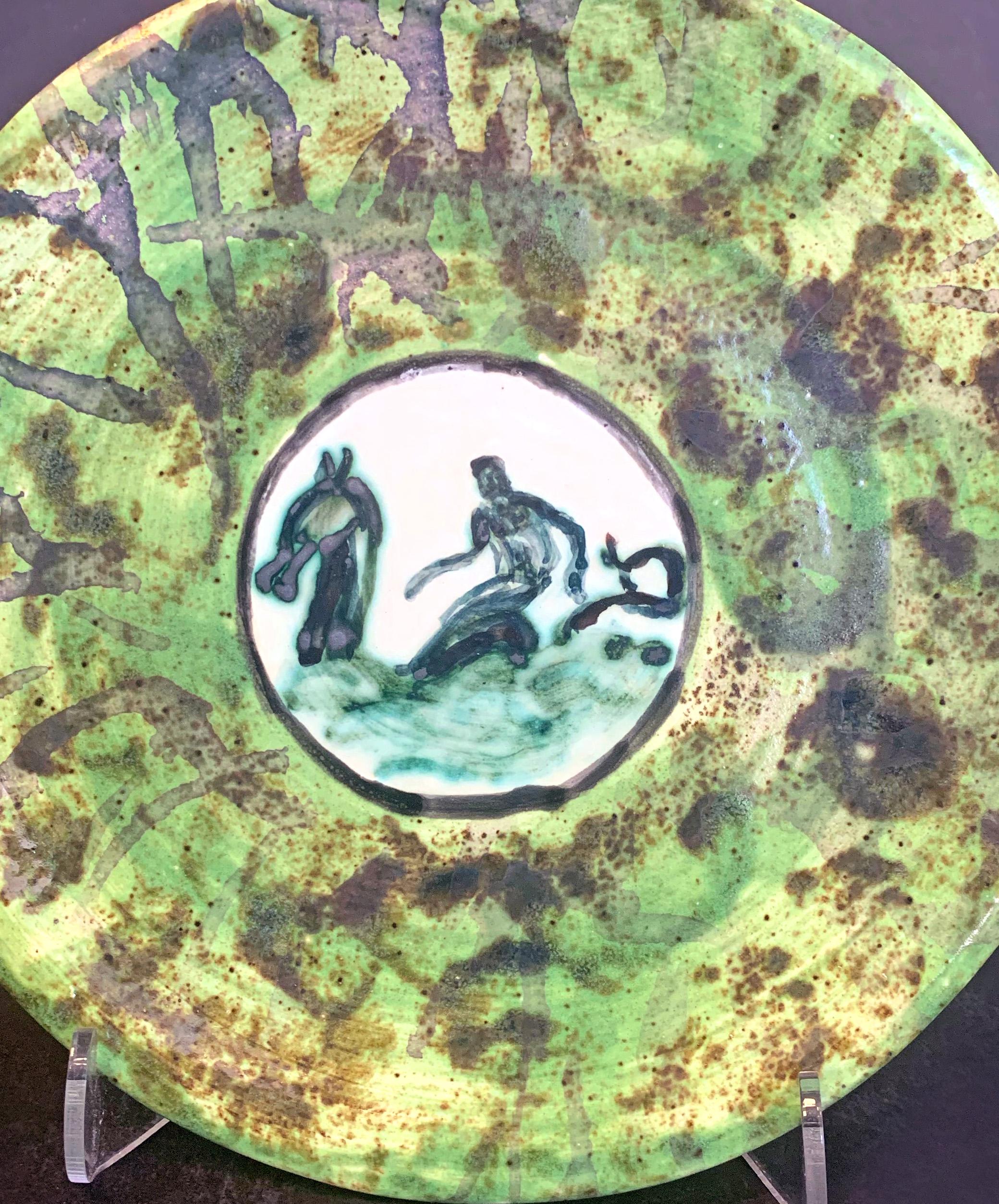 A superb example of Jean Mayodon's fascination with mythological figures, especially gods and goddesses cavorting in the sea, this fine Art Deco plate depicts Neptune riding a sea dragon or hippocampus in the central medallion. The outer border of