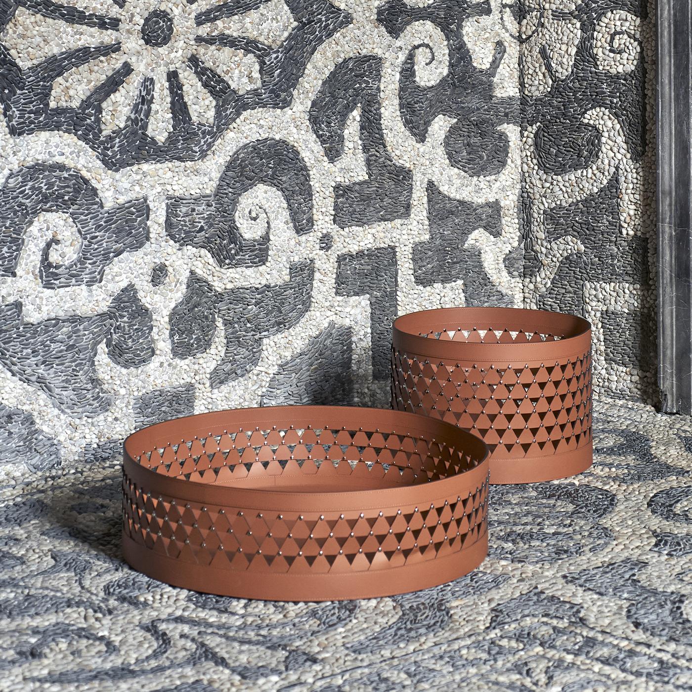 Il cesto rotondo Nereide 45 di Studiopepe presenta un caratteristico design a reticolo con ritagli a forma di diamante che proiettano dinamici motivi di luce e ombra. Le sue dimensioni rotonde e medie lo rendono un pezzo d'accento versatile, adatto