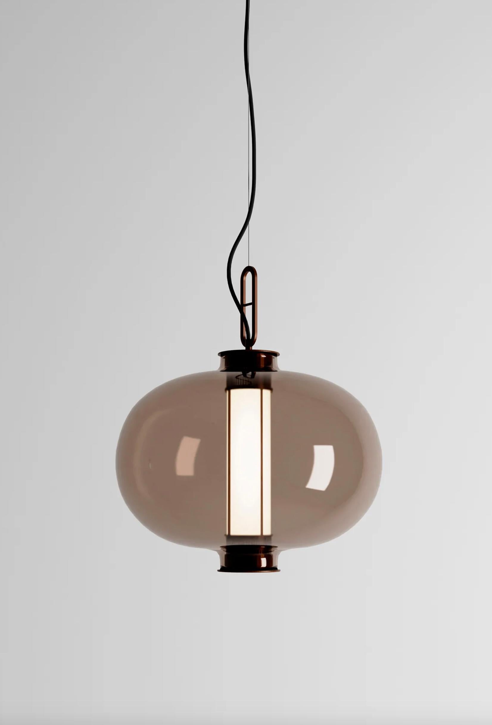 Neri & Hu Bai T Ba Ba Bronzo - Lampada a Sospensione con Diffusore in Vetro Ambrato Per Parachilna 

Questa collezione si ispira alle tradizionali lanterne cinesi. Questa versione, tuttavia, è molto sofisticata. Realizzato con una struttura