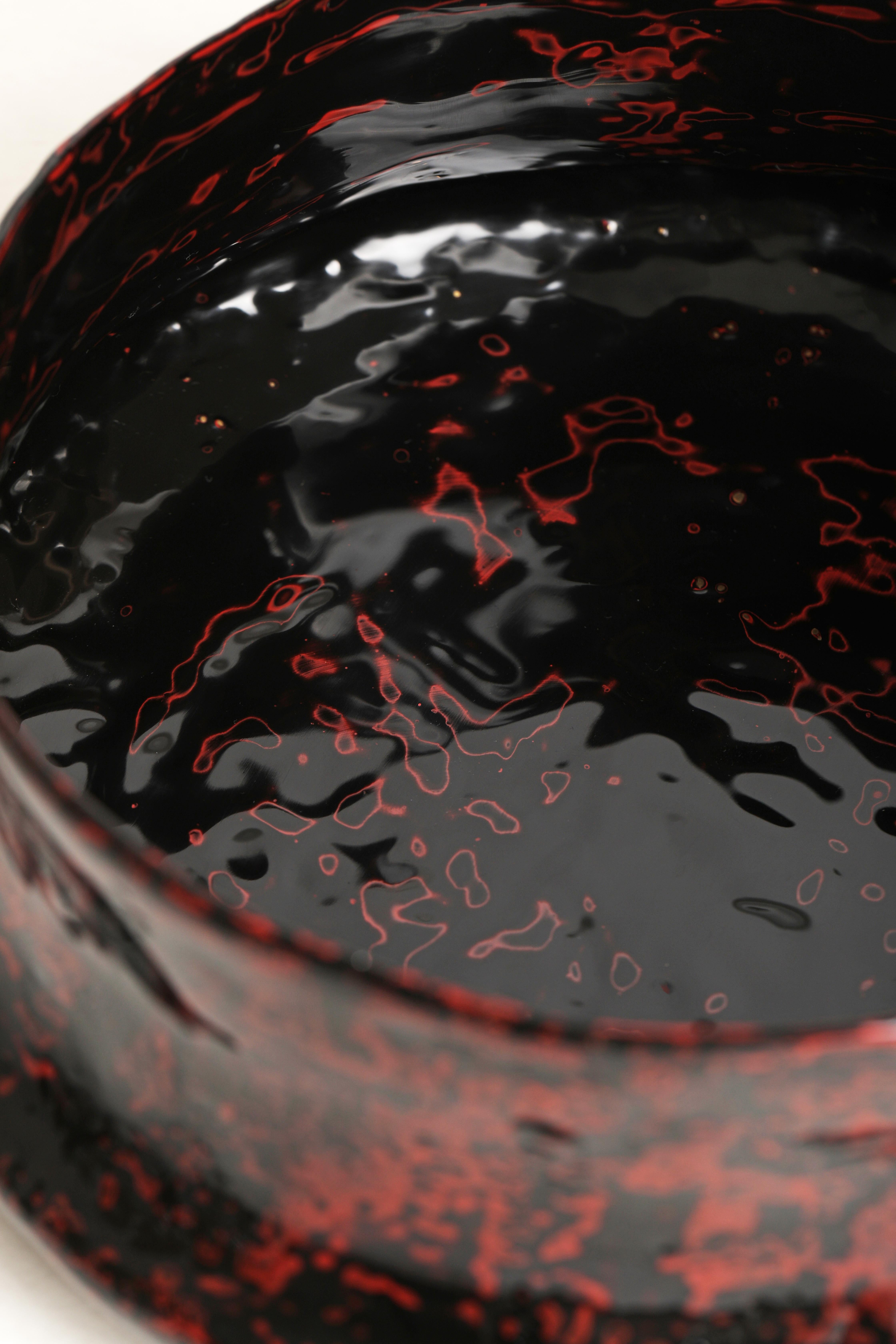 Un sontuoso vaso inclinato ricco di texture e colori. La lacca Urushi nei classici colori rosso e nero viene applicata su una superficie di lino grezzo fusa in bronzo prima di essere strofinata per mostrare gli strati.