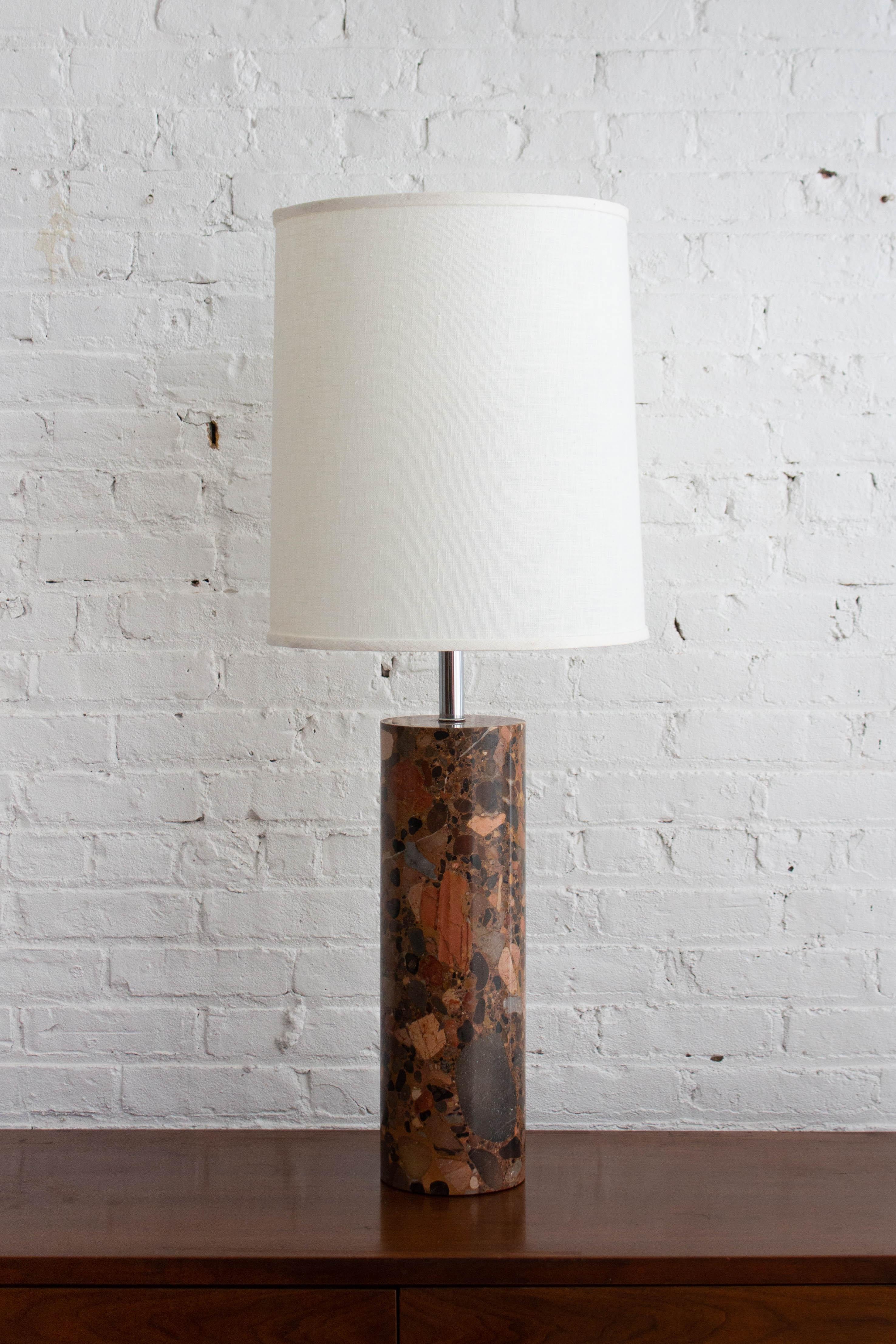 A cylindrical solid terrazzo marble table lamp attributed to Walter Von Nessen. Chrome hardware with full range dimmer socket. Beautiful color variations throughout the stone, ranging from reds to beiges and grays. Pair available, sold individually.