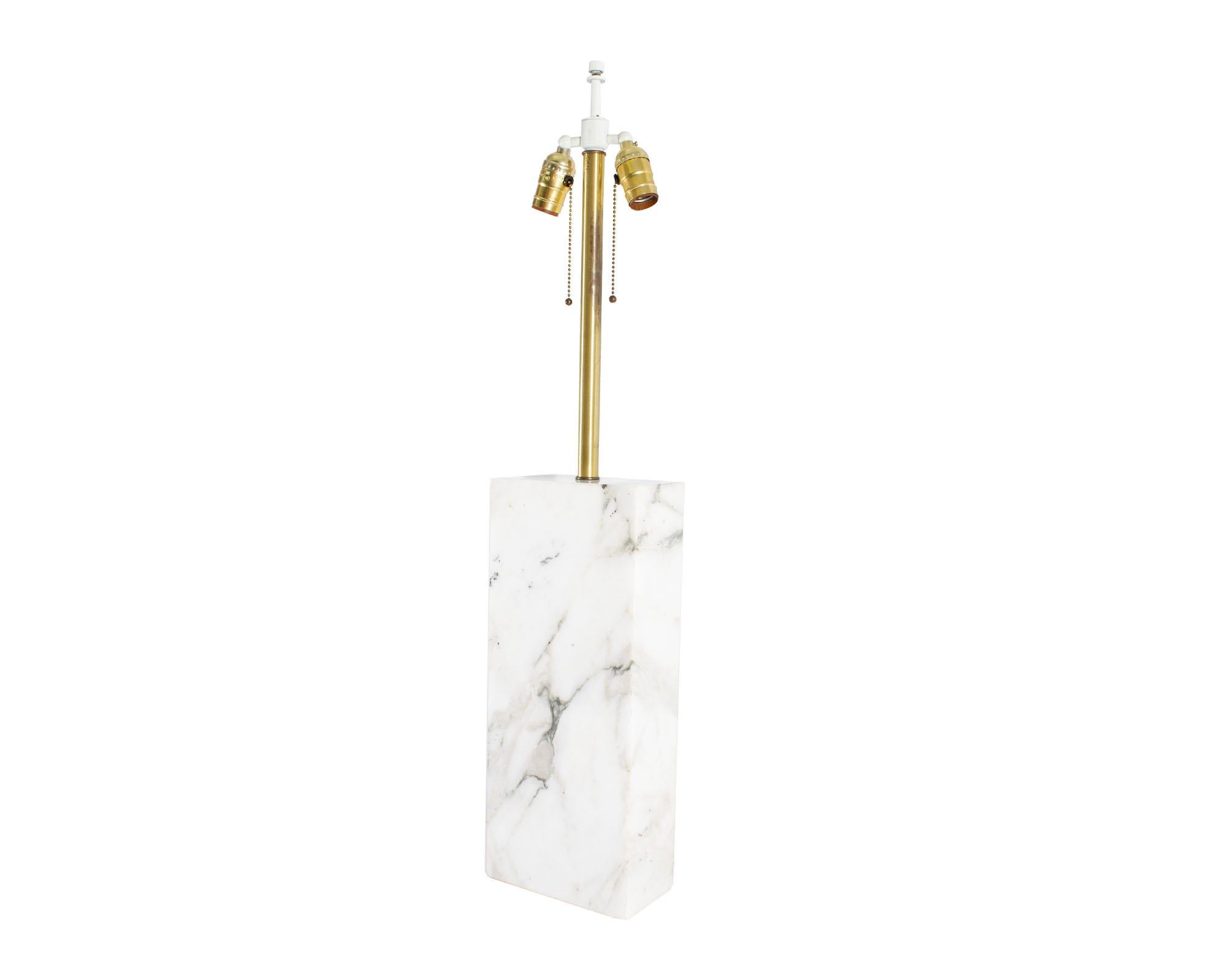 A stone table lamp by the American lighting company Nessen Studios. This dual-bulb design is made of a block of white and gray marbled stone with brass tone and white hardware. Accents include the beaded chains and cream-colored cord. The lamp is