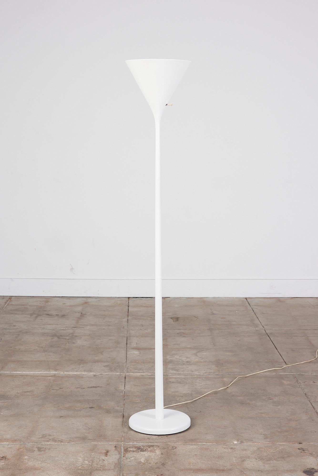 White enamel floor lamp by Nessen Studios. The modern lamp features a cone shade that directs light upwards and an on/off switch at the bottom of the shade.

Dimensions: 11
