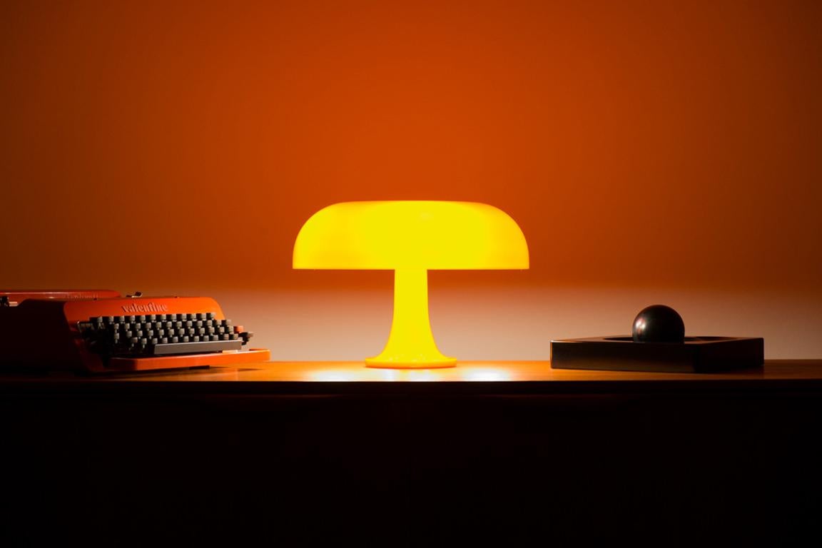 Lampe de table 'Nessino' de Giancarlo Mattioli en orange pour Artemide.

Cette lampe est devenue une icône du design, avec sa forme de champignon et ses teintes orange ou blanches vives. Lancé en 1967, le Nessino était une merveille de moulage par