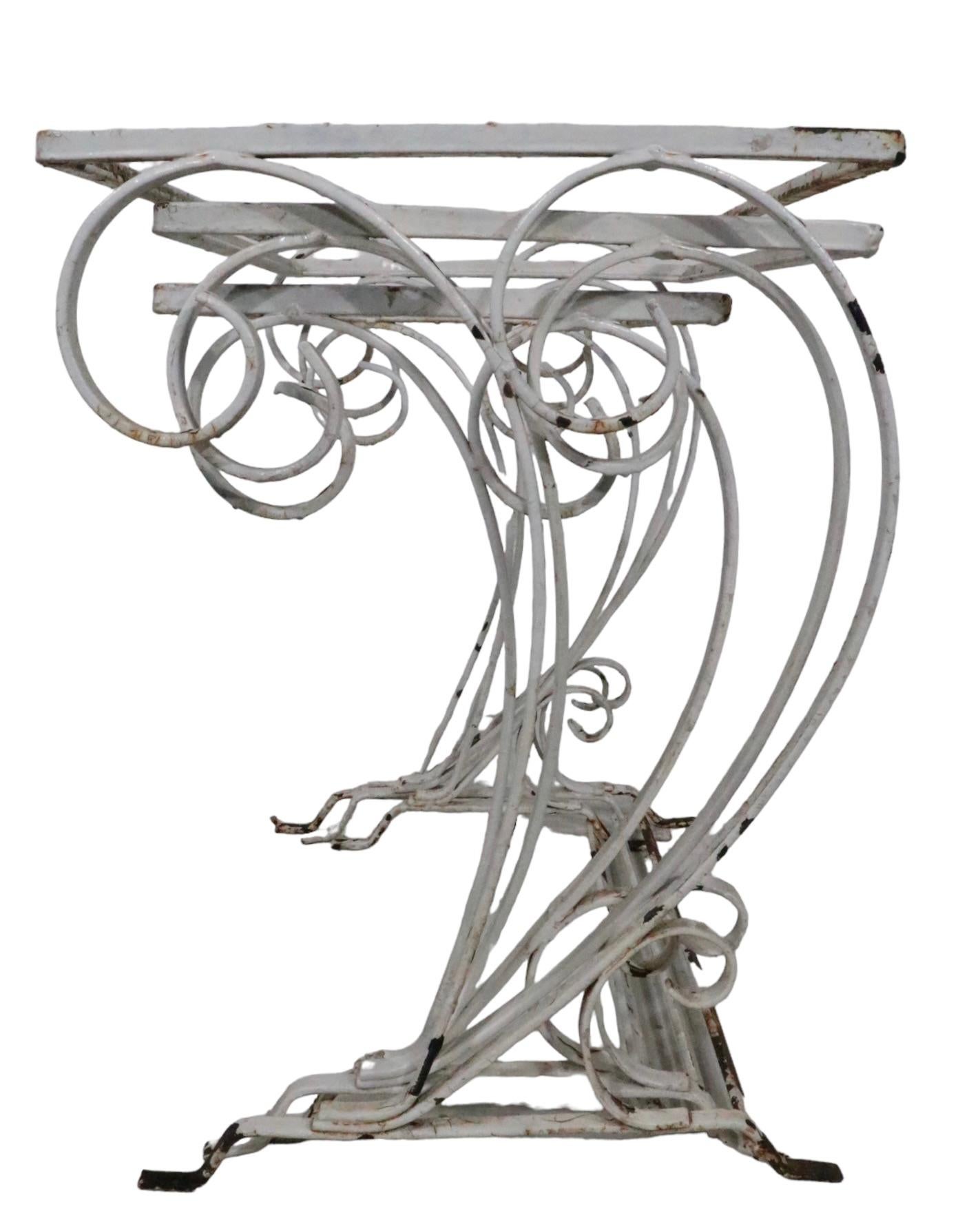 Chic set of three graduated size nesting tables in wrought iron, attributed to Salterini. The tables feature a decorative flowing wave like repeat as vertical supports, which support the rectangular top. The tables are all structurally sound, and