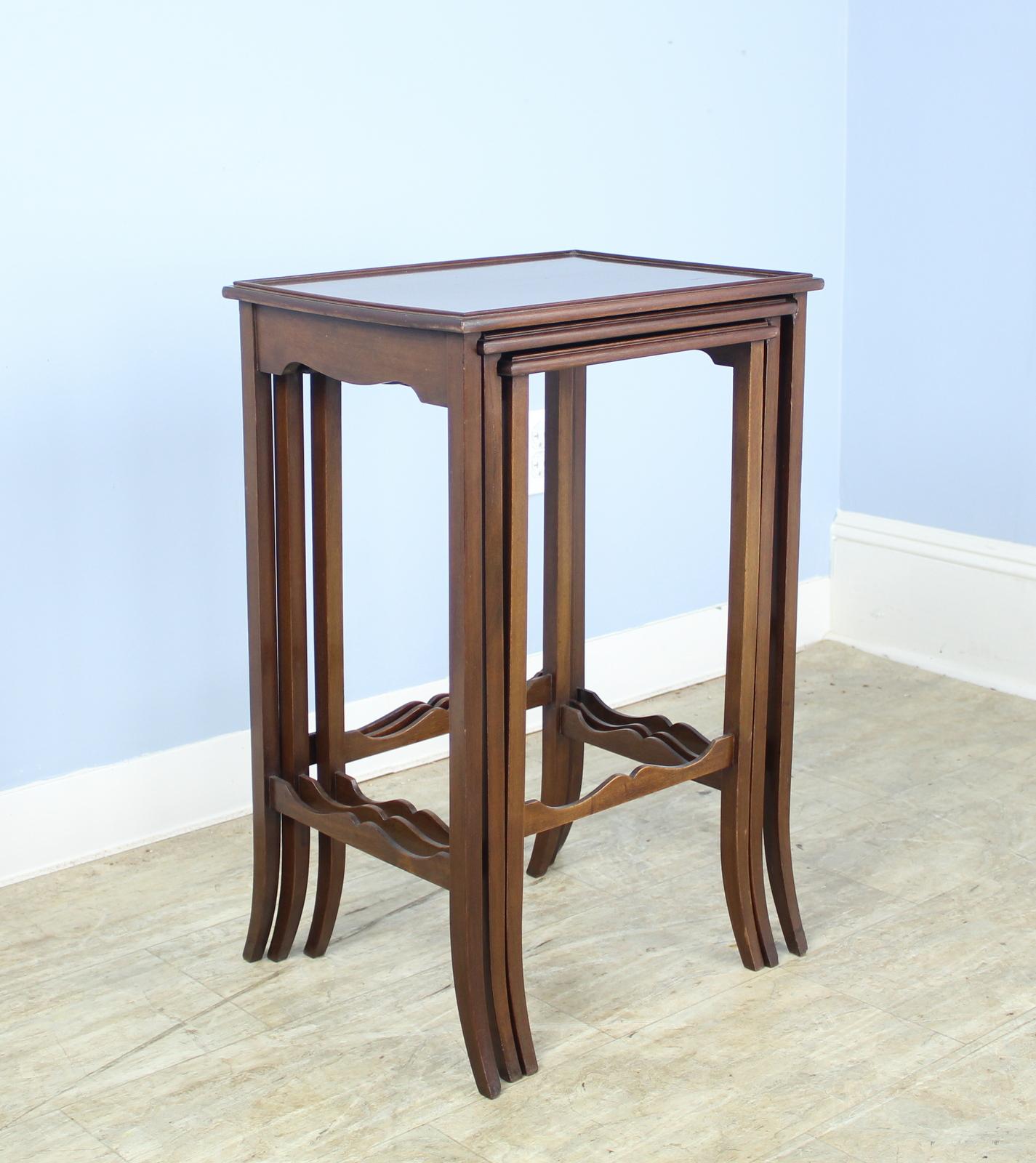 These three elegant tables stand on four long, slender legs which flare out at the bottom and are joined by shaped stretchers. The tops are good quality mahogany with a small raised gallery on each table. The mddle table has a small area of wear,