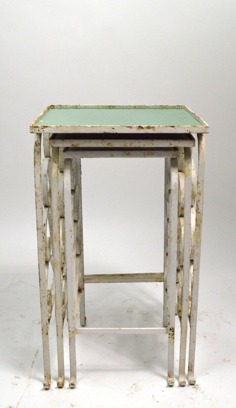 Very stylish Art Deco nesting tables, attributed to Salterini. Wrought iron bases with green glass tops. Finish shows cosmetic wear, normal and consistent with age. We offer custom powder coating, and or can replace the glass tops, if you want a