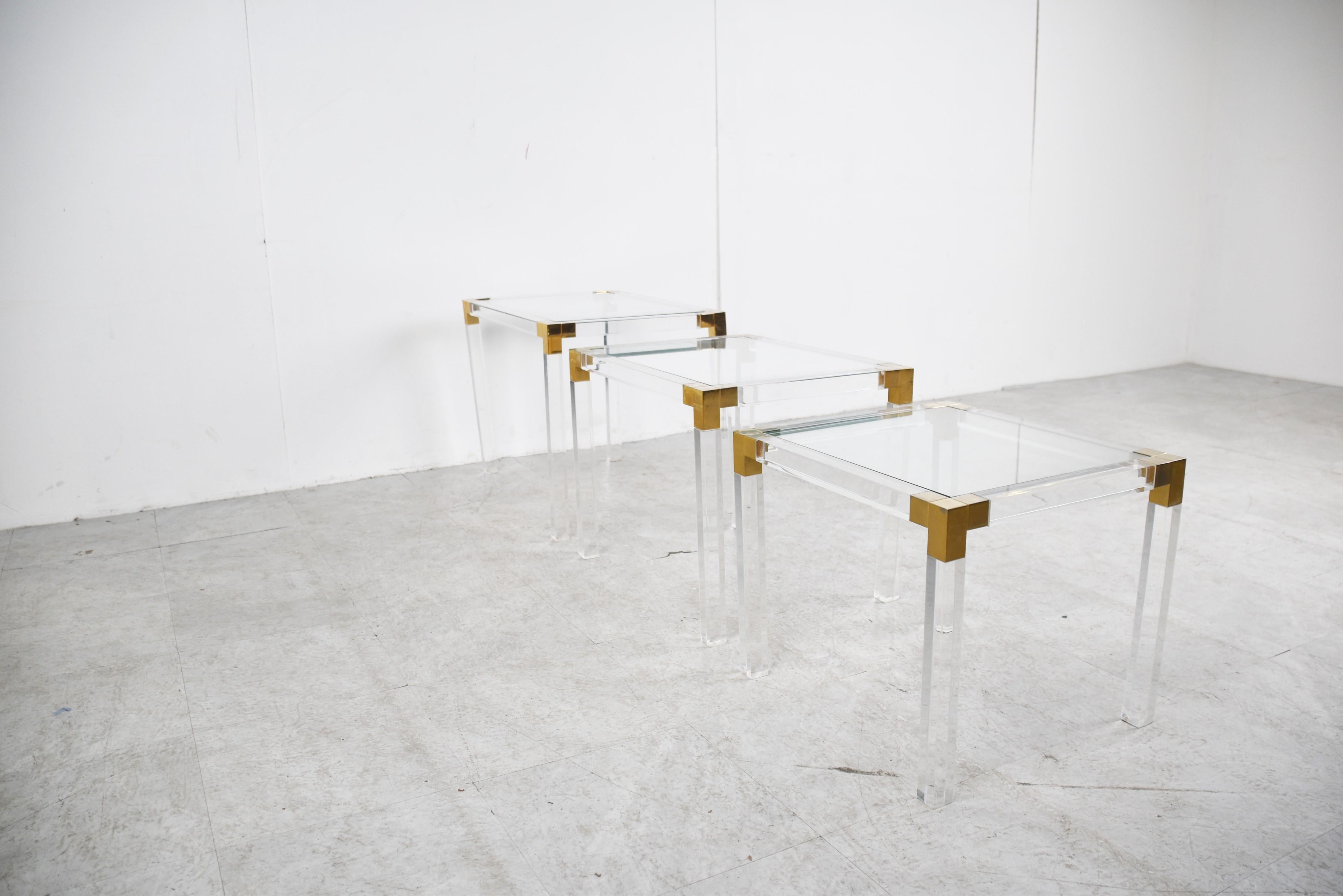 Elegant set of Lucite and Brass Nesting Tables with inset clear glass tops. 

Nice brass and lucite frames.

Charles Hollis Jones style

Excellent condition

1970s - France

The dimensions shown are from the largest table

Height: 45cm