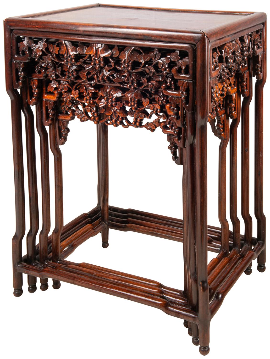 Un nid de quatre tables chinoises en bois dur de bonne qualité, chacune avec une décoration de feuilles de vigne et de raisins bien sculptée sur la frise. Dessus en bois dur poli, soulevés de pieds circulaires sculptés unis par une civière en