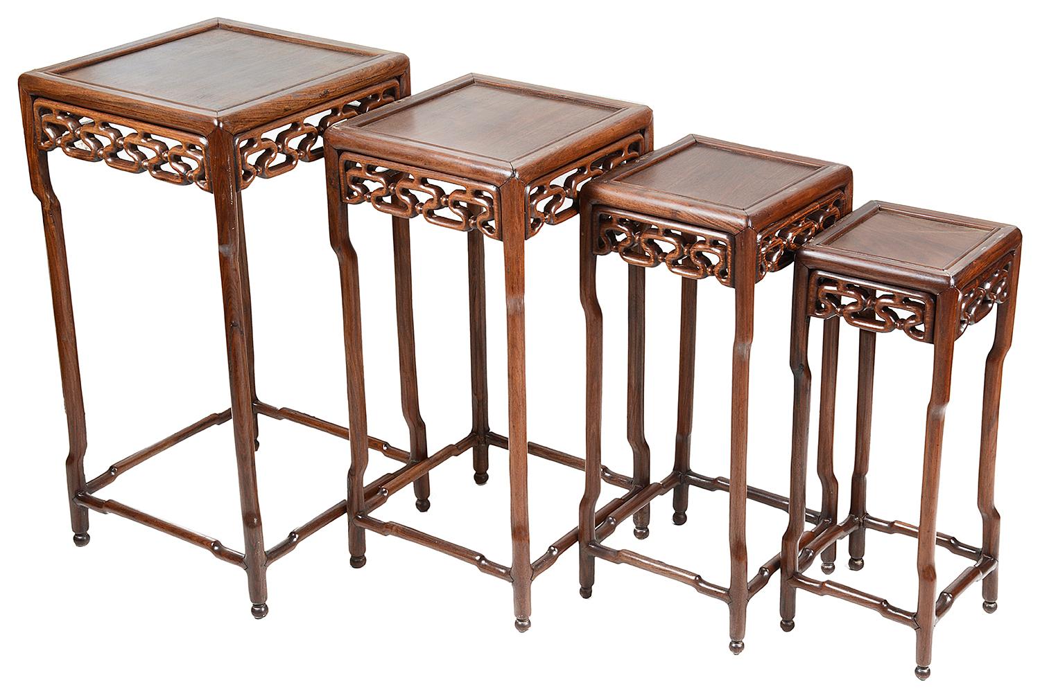 A good quality nest of four late 19th century Chinese hardwood tables, each with inset tops, carved scrollwork frieze decoration, raised on shaped supports and united with stretchers below.