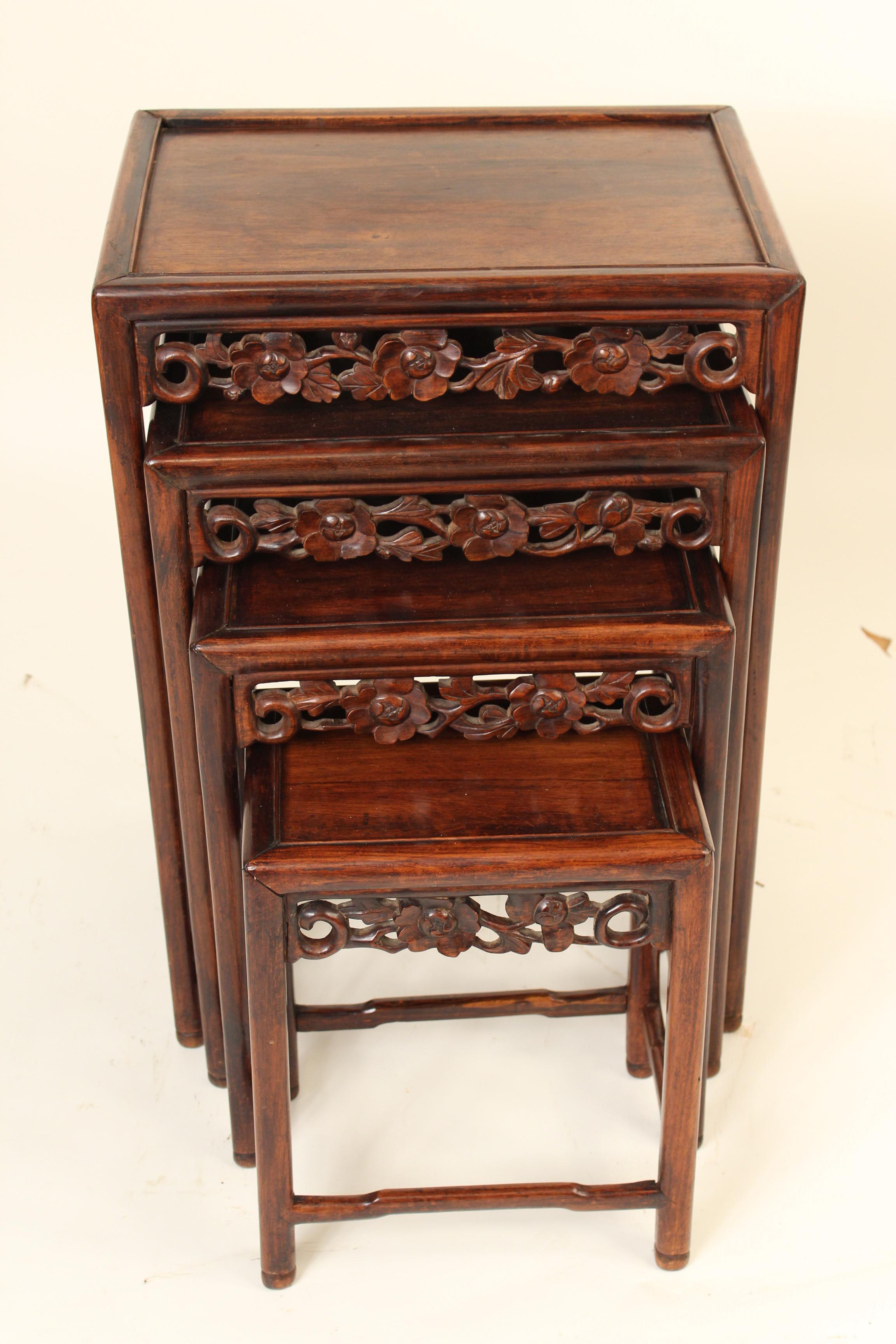 Nest of four Chinese carved teak wood tables, circa 1930. The bottom of the largest table stamped China. The dimensions of the largest table that the other tables will fit under is, height 28.25