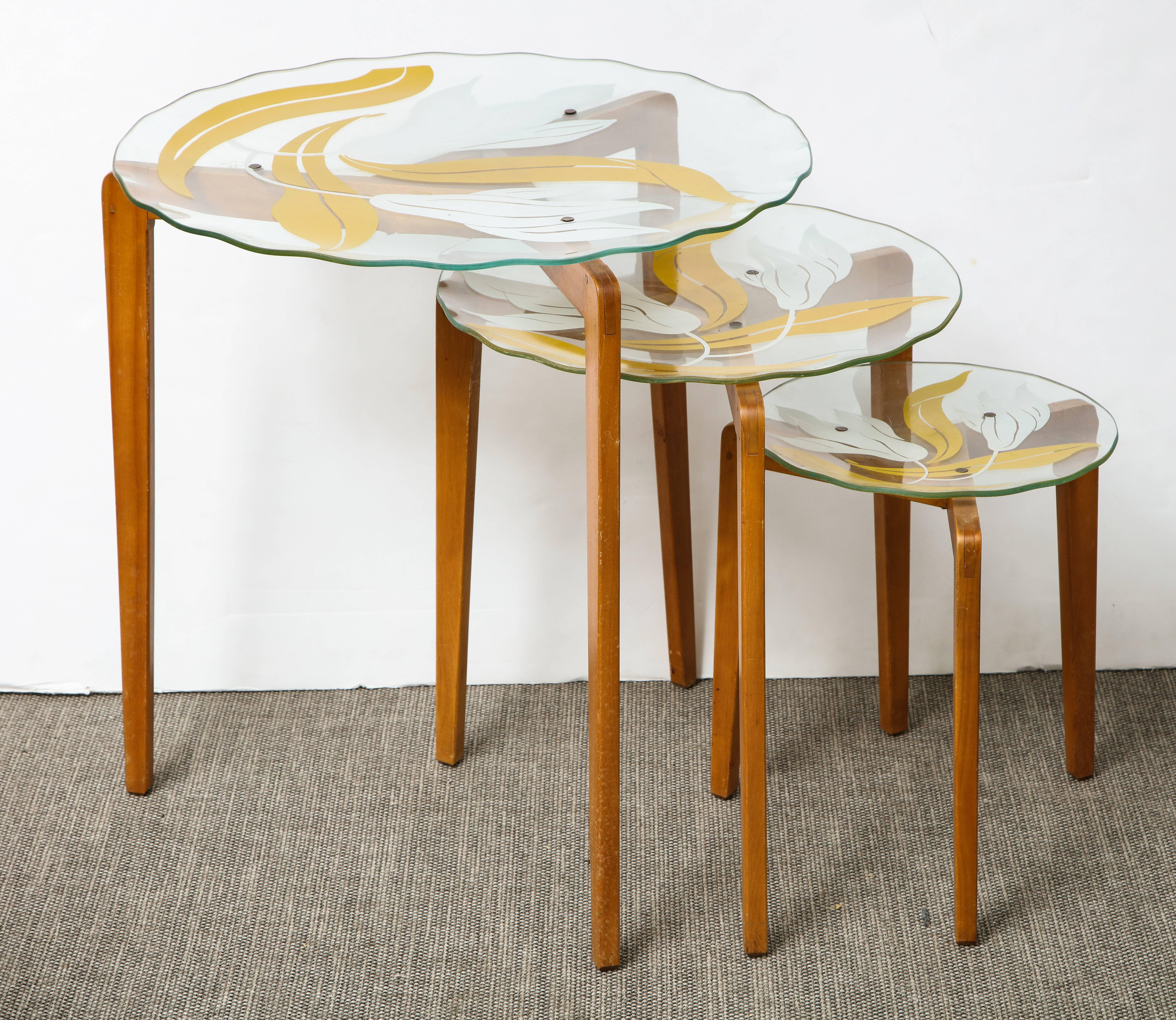 A wonderful nest of Italian glass top tables with painted floral decoration on tapered wood legs in the style of Gio Ponti.