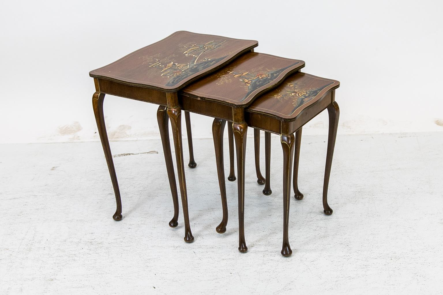 This nest of chinoiserie tables has raised lacquer chinoiserie figures in landscapes and floral decorations. All four sides are serpentine shaped. The legs are cabriole and terminate in pad feet.