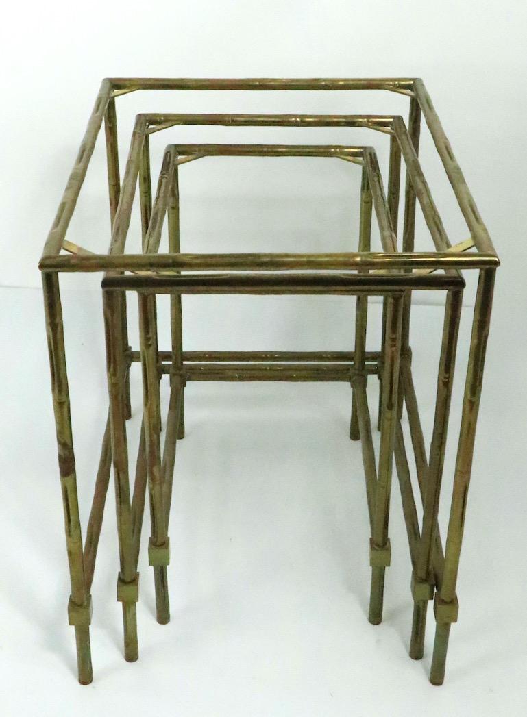 Nest of three brass faux bamboo nesting tables, probably Italian made in the French style. This stylish and chic set consists of three graduated size tables which nest into the largest one to store easily. The tables originally had glass tops, they
