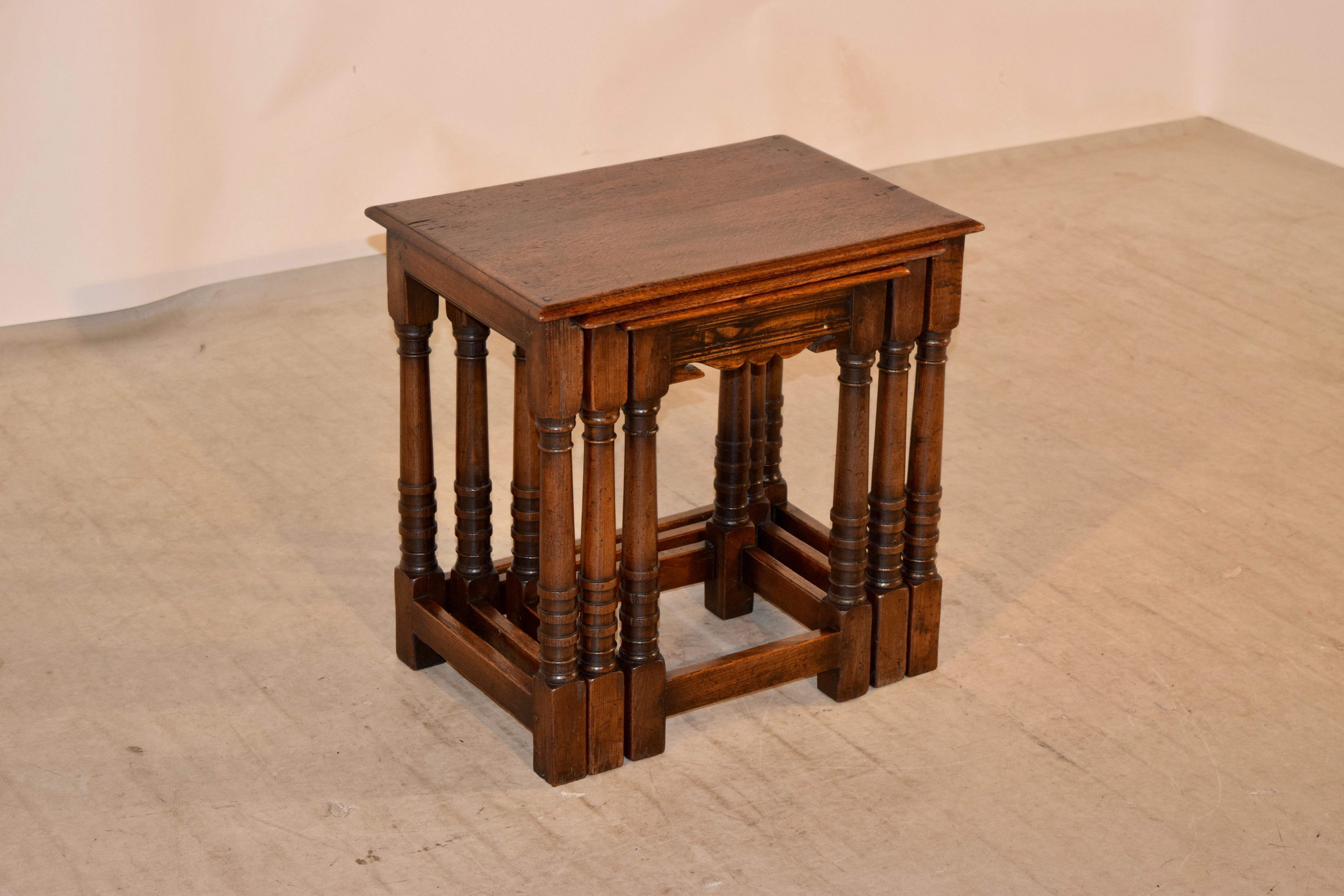 Nest of three English oak tables, circa 1900. The tops have beveled edges and pegged construction throughout. The aprons are simple, and the smallest table has a scalloped front apron for added effect. Supported on hand-turned legs, joined by simple