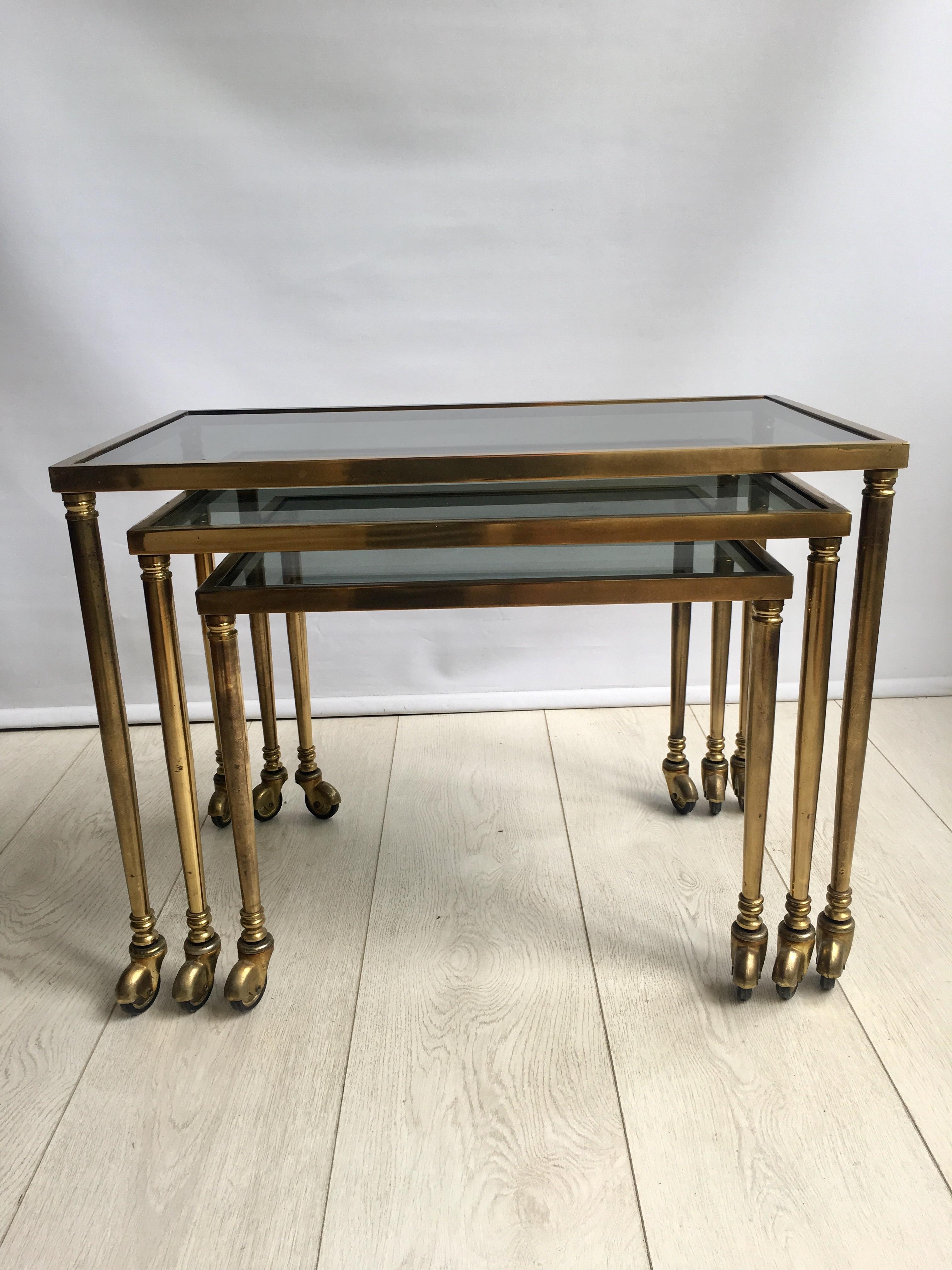 A nest of 3 graduated brass and smoked glass occasional/side tables from France.

Lacquered brass frames with tapered legs on castors.

Lovely patina to the frames.

Measures: Largest table 43 cm high x 58 cm long x 34 cm deep,

circa 1960.